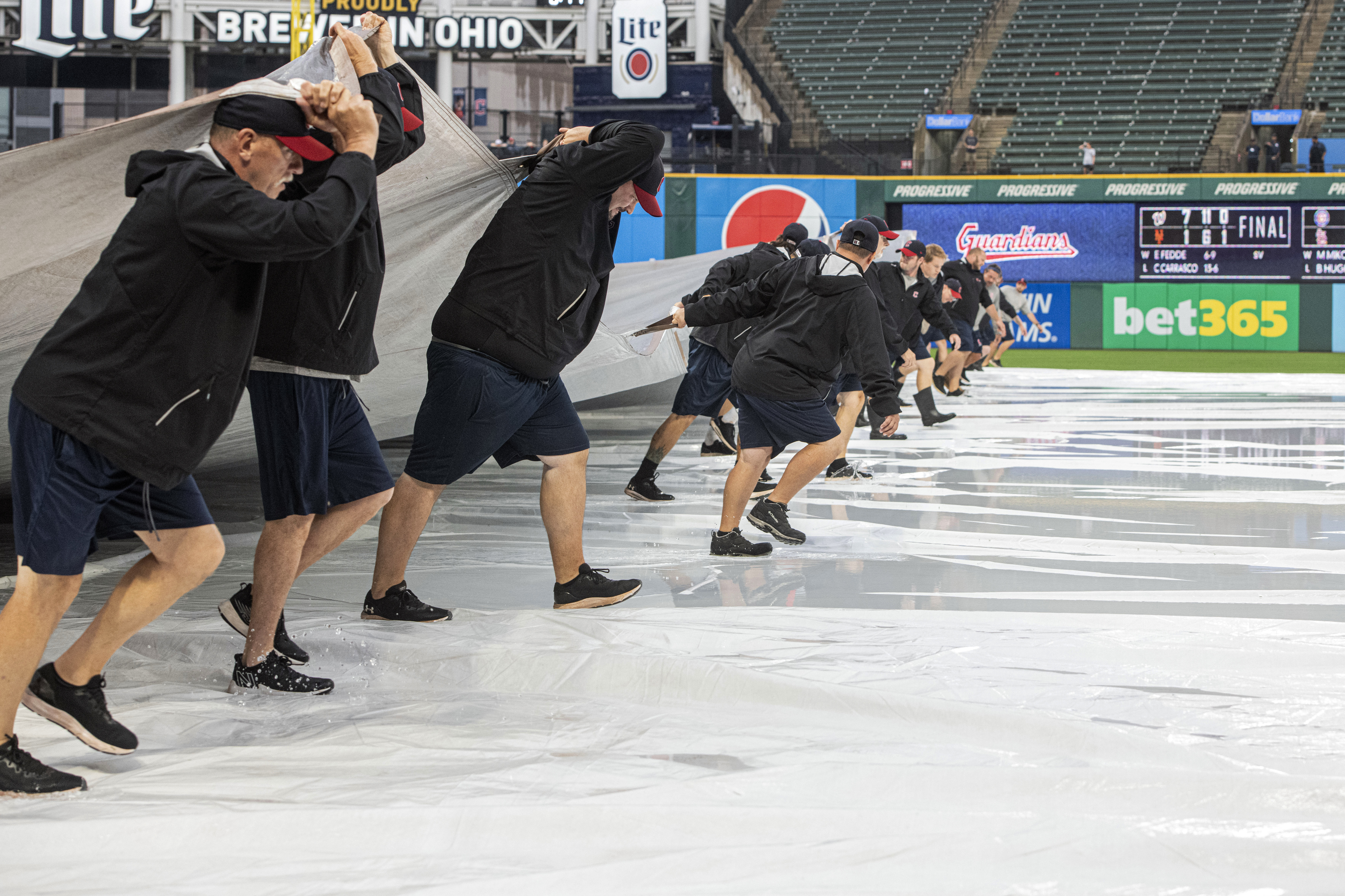 Members of the Cleveland Guardians grounds crew remove the tarp from the infield as they attempt to get the field ready to play during the fourth inning of a baseball game between the Seattle Mariners and the Guardians in Cleveland, Sunday, Sept. 4, 2022. 