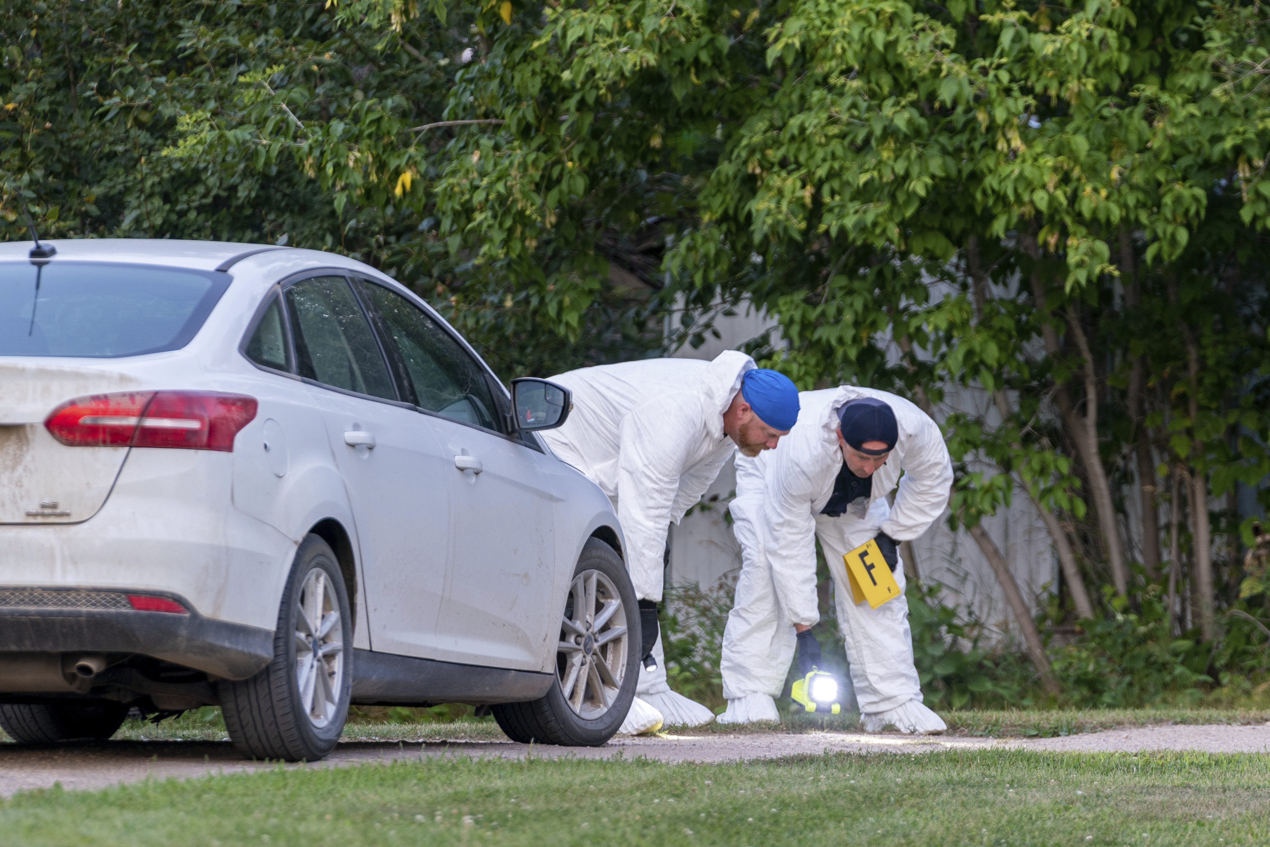 Investigators examine the ground at the scene of a stabbing in Weldon, Saskatchewan on Sunday. A series of stabbings at an Indigenous community and at another in the village of Weldon left multiple people dead and others wounded.