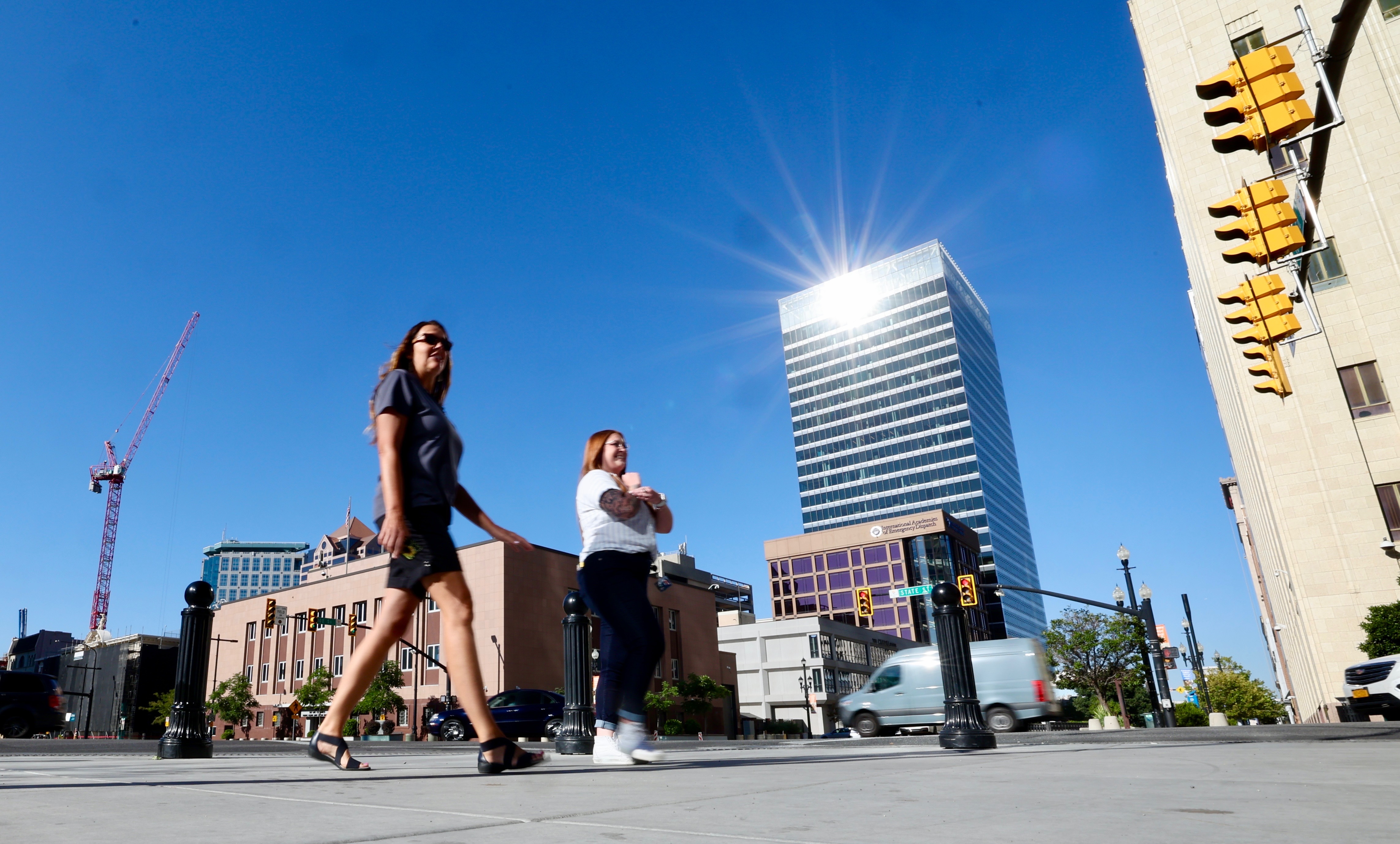The sun reflects off of the 111 Main building as two women walk on the sidewalk along State Street in Salt Lake City Tuesday morning. Temperatures are expected to remain near or above 100 degrees in Salt Lake City through Thursday, breaking more heat records in the process.