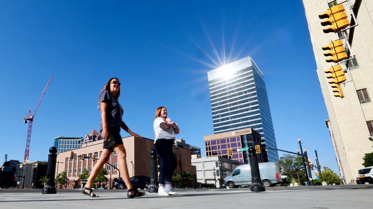 The sun reflects off the 111 Main building as two women walk on the sidewalk along State Street in Salt Lake City on Sept. 6, 2022. Salt Lake County said Friday it is extending cool zone hours at five locations with record-breaking heat in the forecast.