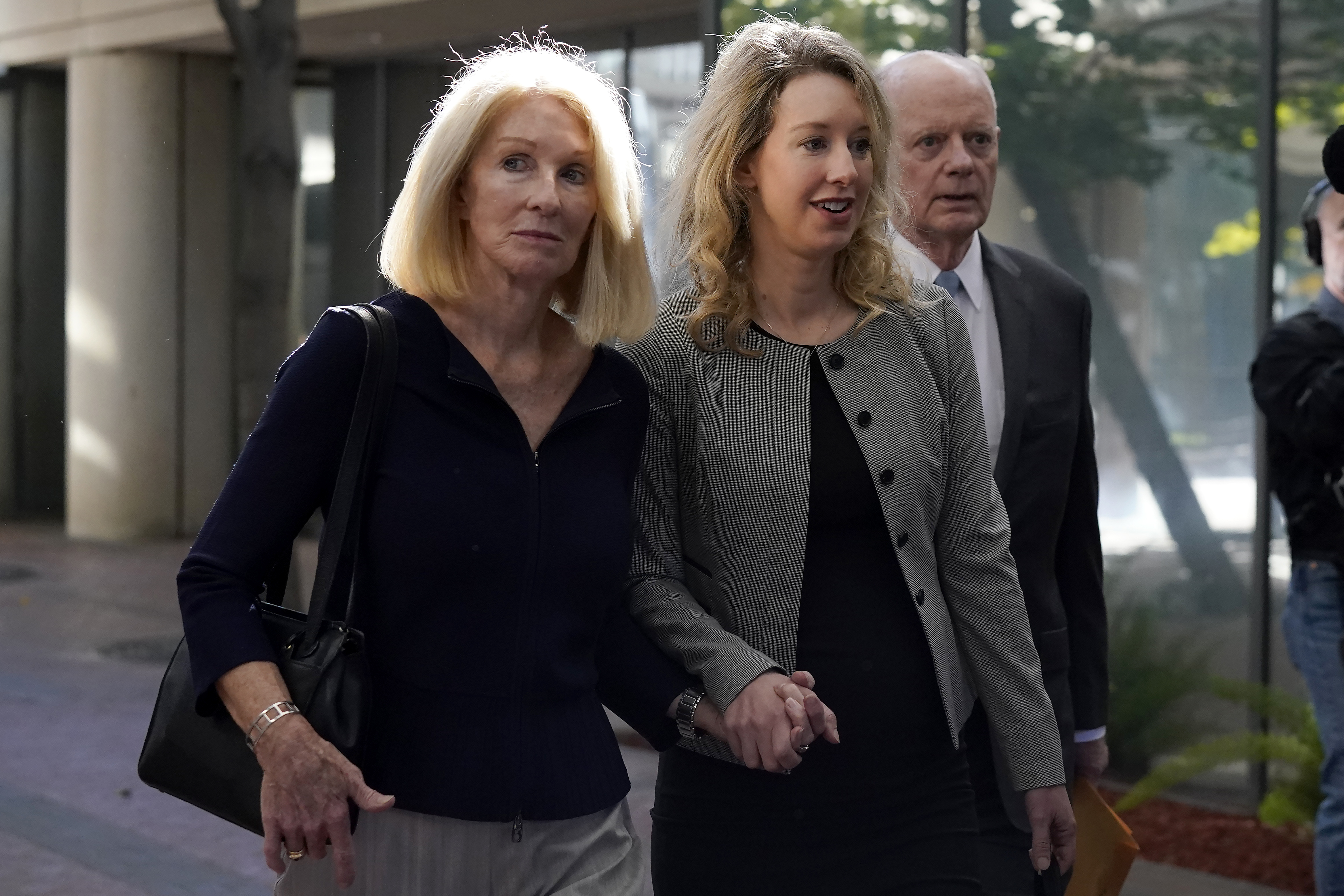 Former Theranos CEO Elizabeth Holmes, center, her mother, Noel Holmes, left, and father, Christian Holmes IV, arrive at federal court in San Jose, Calif., Thursday. Elizabeth Holmes on Tuesday requested a new trial in documents asserting that a key witness who testified against her now regrets the role he played in her criminal conviction for lying to investors about the flaws in a blood-testing technology that she had hailed as a medical breakthrough. 