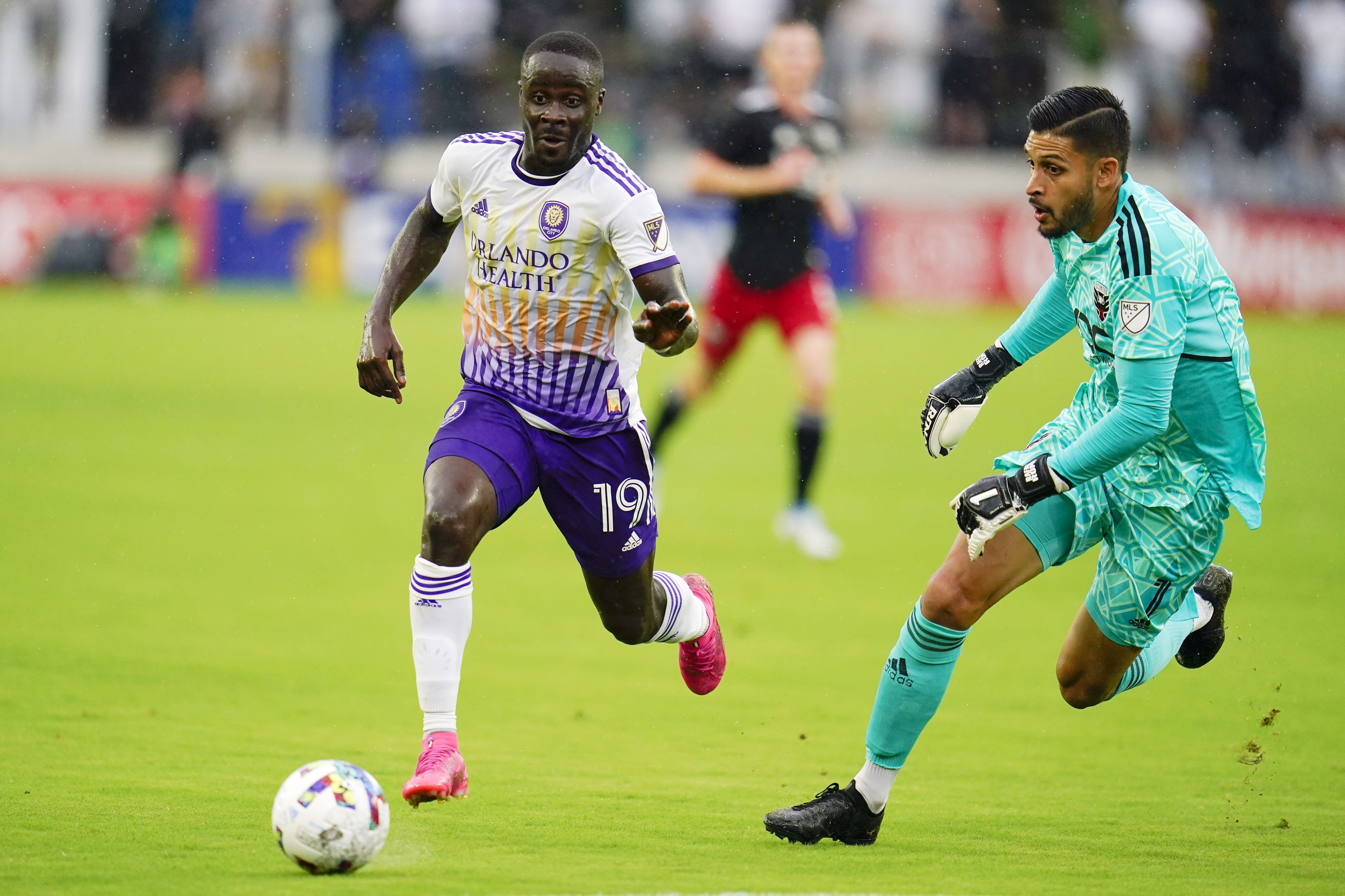 FILE - Orlando City forward Benji Michel, left, attacks as D.C. United goalkeeper Rafael Romo leaves his penalty area to defend during the first half of an MLS soccer match, Sunday, July 31, 2022, in Washington. Orlando City’s pursuit of its first trophy in the U.S. Open Cup is personal for Benji Michel, who grew up in Orlando and was signed by the Lions as a homegrown player. 