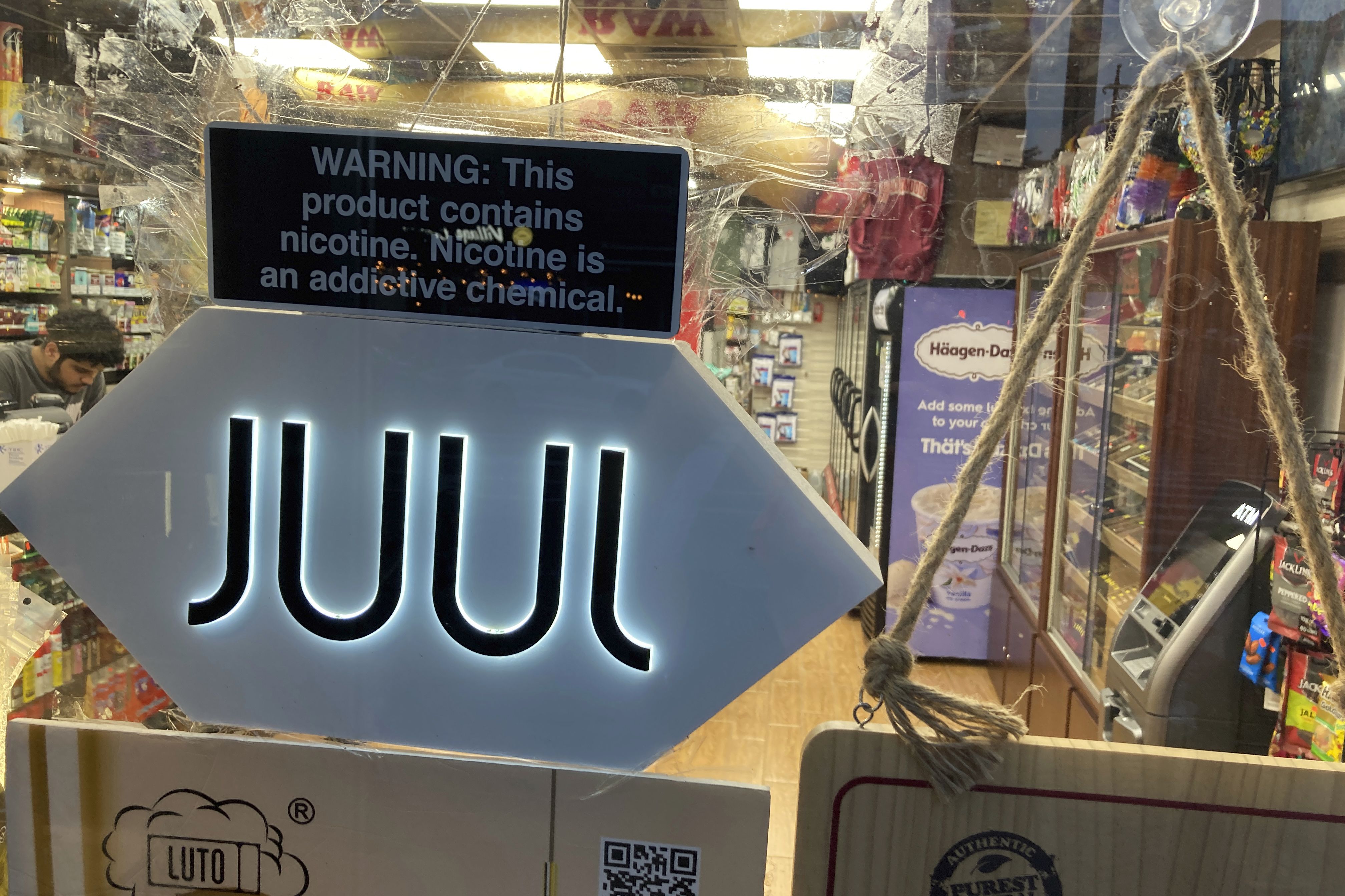 A Juul electronic cigarette sign hangs in the front window of a bodega convenience store in New York City on June 25. In a deal announced Tuesday, Juul Labs will pay nearly $440 million to settle a two-year investigation by 33 states into the marketing of its high-nicotine vaping products.