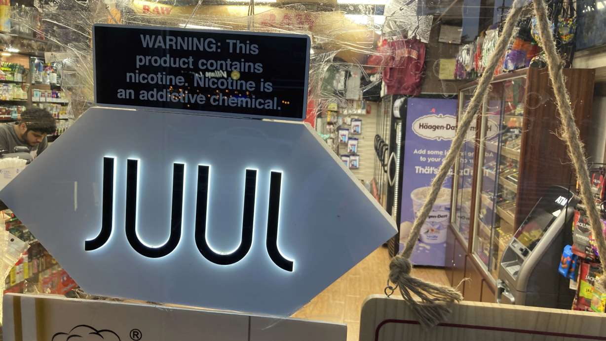 A Juul electronic cigarette sign hangs in the front window of a bodega convenience store in New York City on June 25. In a deal announced Tuesday, Juul Labs will pay nearly $440 million to settle a two-year investigation by 33 states into the marketing of its high-nicotine vaping products.