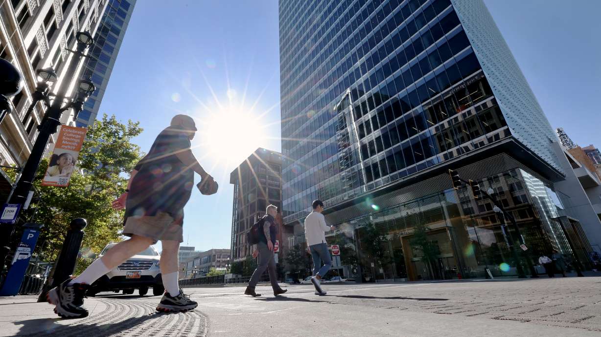 The sun shines down on pedestrians as they walk across the street in Salt Lake City on Tuesday. The city tied its all-time highest temperature record on Wednesday.