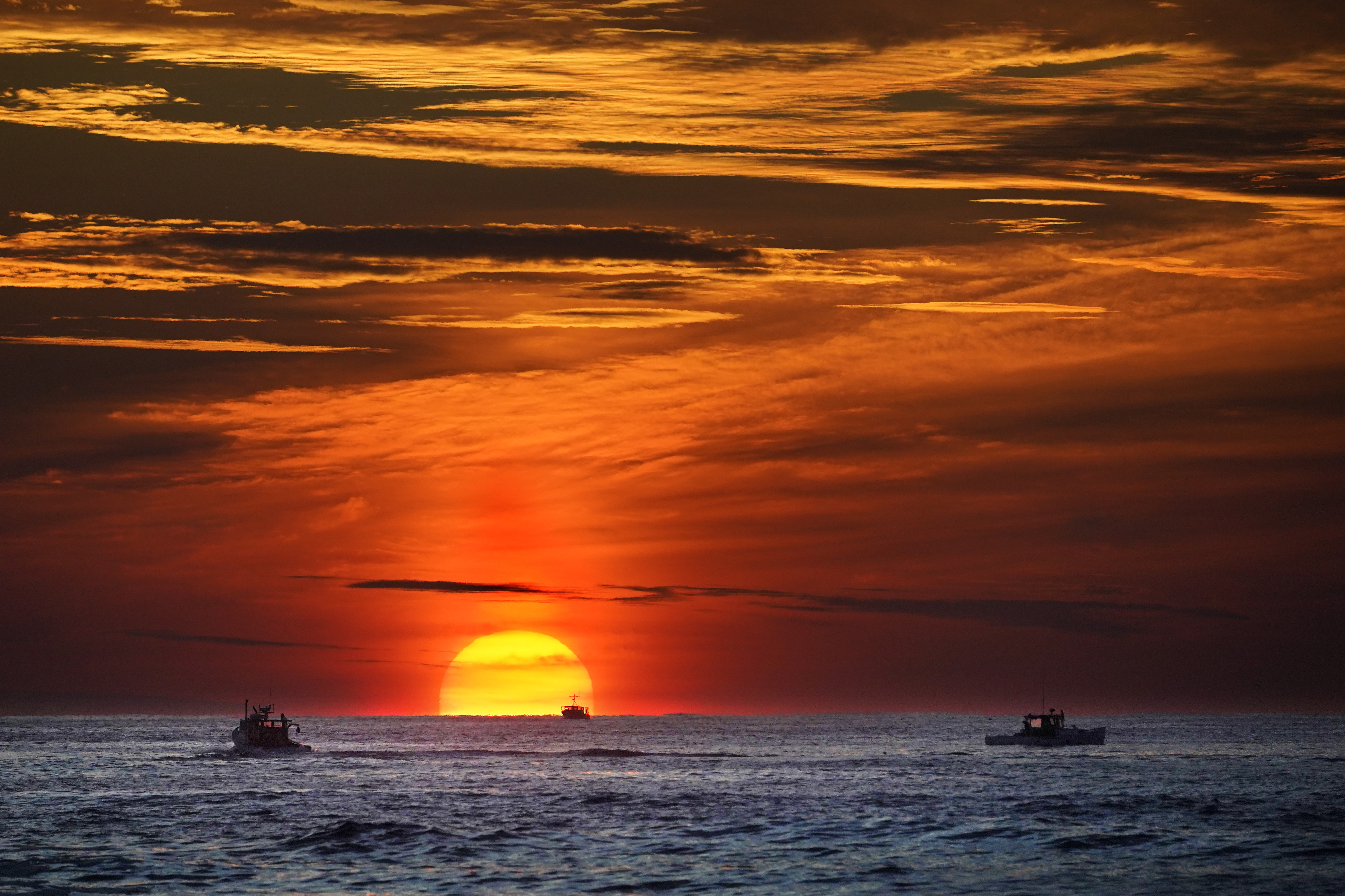 Lobster fishermen are already at work as the sun rises over the Atlantic Ocean, Thursday, off of Kennebunkport, Maine. Some retailers are taking lobster off the menu after an assessment from an influential conservation group that the harvest of the seafood poses too much of a risk to rare whales and should be avoided. 