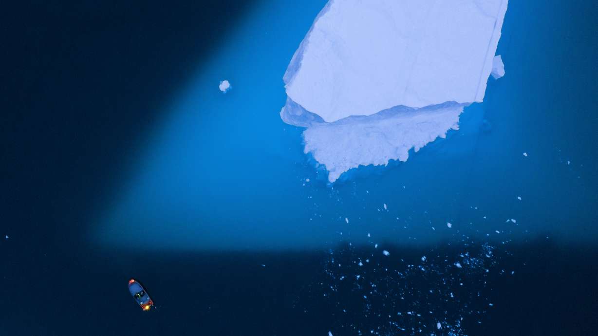 A boat navigates next to a large iceberg in eastern Greenland on Aug. 15, 2019. Even if the world somehow manages to limit future warming to the strictest international temperature goal, four Earth-changing climate “tipping points” are still likely to be triggered like the irreversible collapse of the Greenland ice sheets, with a lot more looming as the planet heats more after that, a new study said.