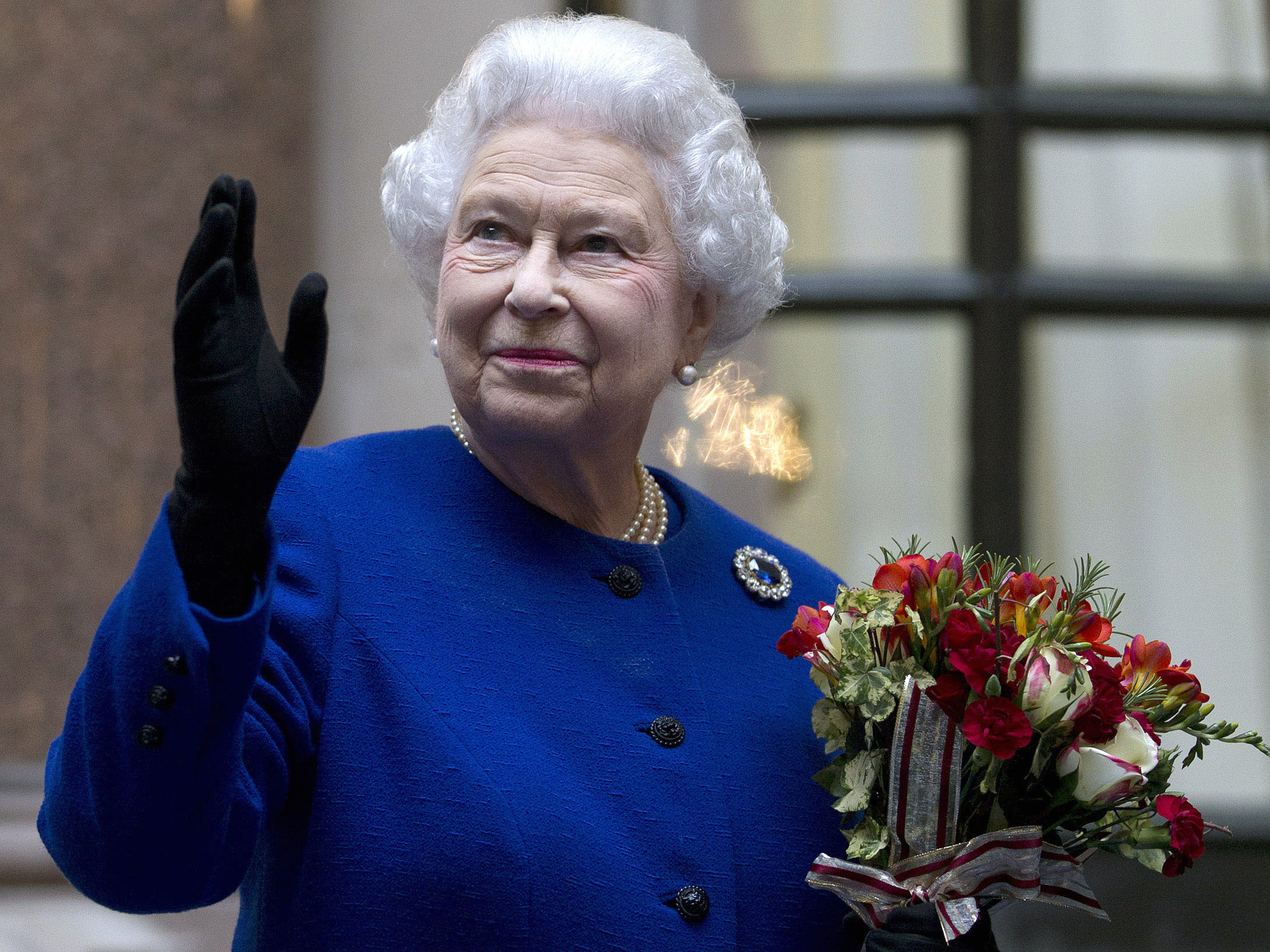 Britain's Queen Elizabeth II looks up and waves to members of staff of the Foreign and Commonwealth Office as she ends an official visit which is part of her Jubilee celebrations in London, Dec. 18, 2012. Queen Elizabeth II, Britain’s longest-reigning monarch and a symbol of stability across much of a turbulent century, has died on Thursday.