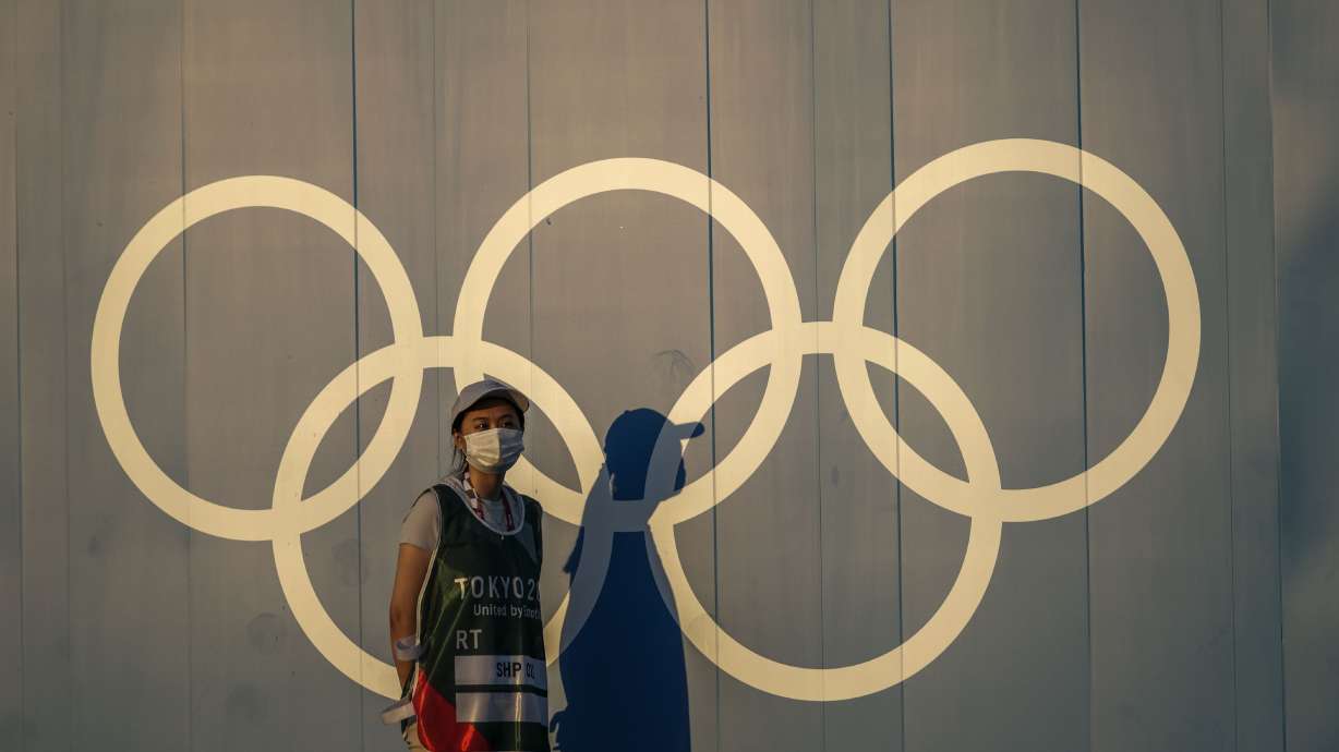 A volunteer walks past the Olympic rings ahead of the 2020 Summer Olympics, in Tokyo on July 22, 2021. The International Olympic Committee announced Thursday a final decision on the host of the 2030 Winter Games now isn't expected until the fall of 2023.