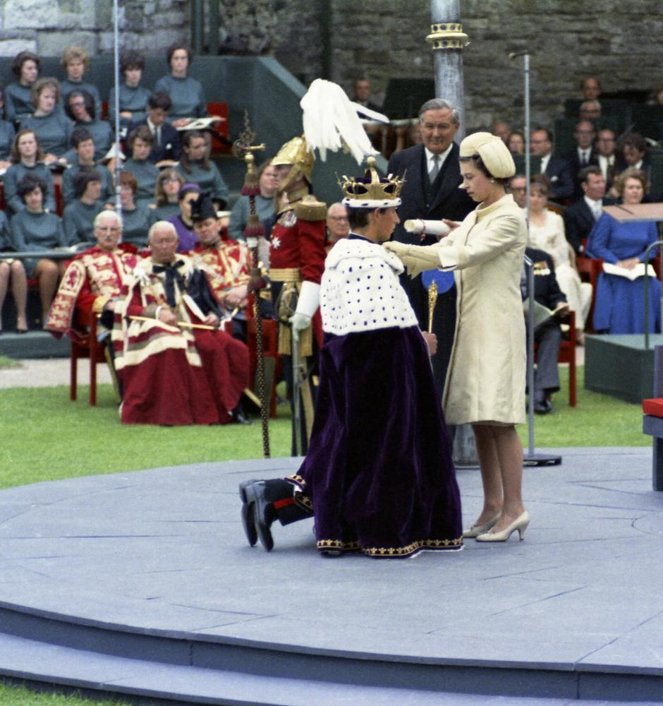 In this July 1, 1969, photo, Prince Charles, kneels before his mother, Britain's Queen Elizabeth II, during the investiture ceremony of the Prince of Wales, at Caernafon Castle in Wales.