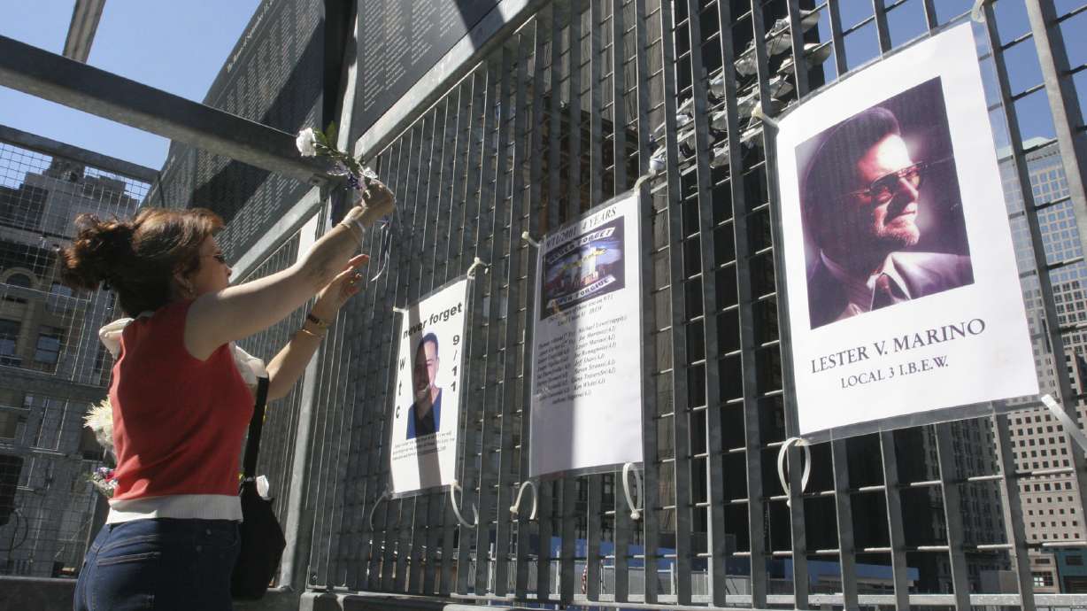 Kathy Haberman places a flower and card in memory of her daughter Andrea Haberman on a gate with other memorial images surrounding ground zero in New York, Sept. 10, 2005. Nearly two decades after his capture in Pakistan, the self-described mastermind of the Sept. 11 terror attacks is still in a legal limbo.
