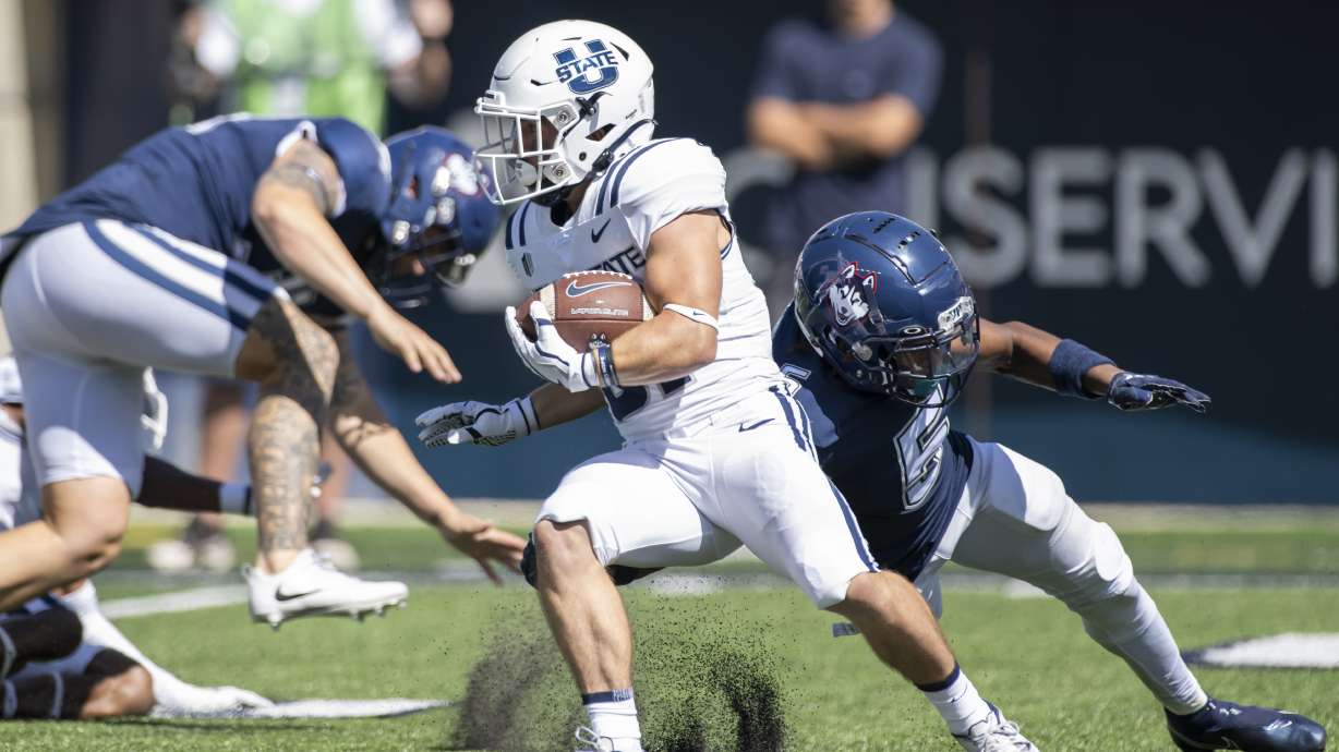 Utah State Aggies running back Cooper Jones (31) avoids the tackle from Connecticut Huskies defensive back Kaleb Anthony (5) during an NCAA football game on Saturday, August, 27, 2022 in Logan, Utah.