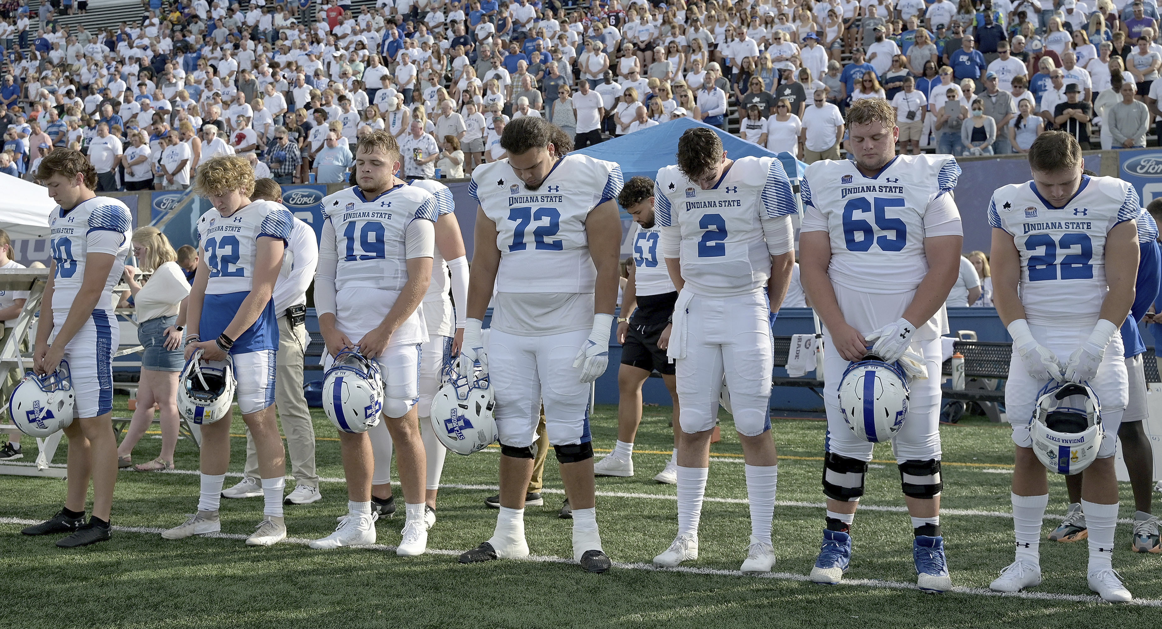 Members of the Indiana State NCAA college football team and fans observe a moment of silence for teammates Caleb VanHooser and Christian Eubanks before the start of the Sycamores' game against North Alabama at Memorial Stadium in Terre Haute, Ind., on Sept. 1, 2022.