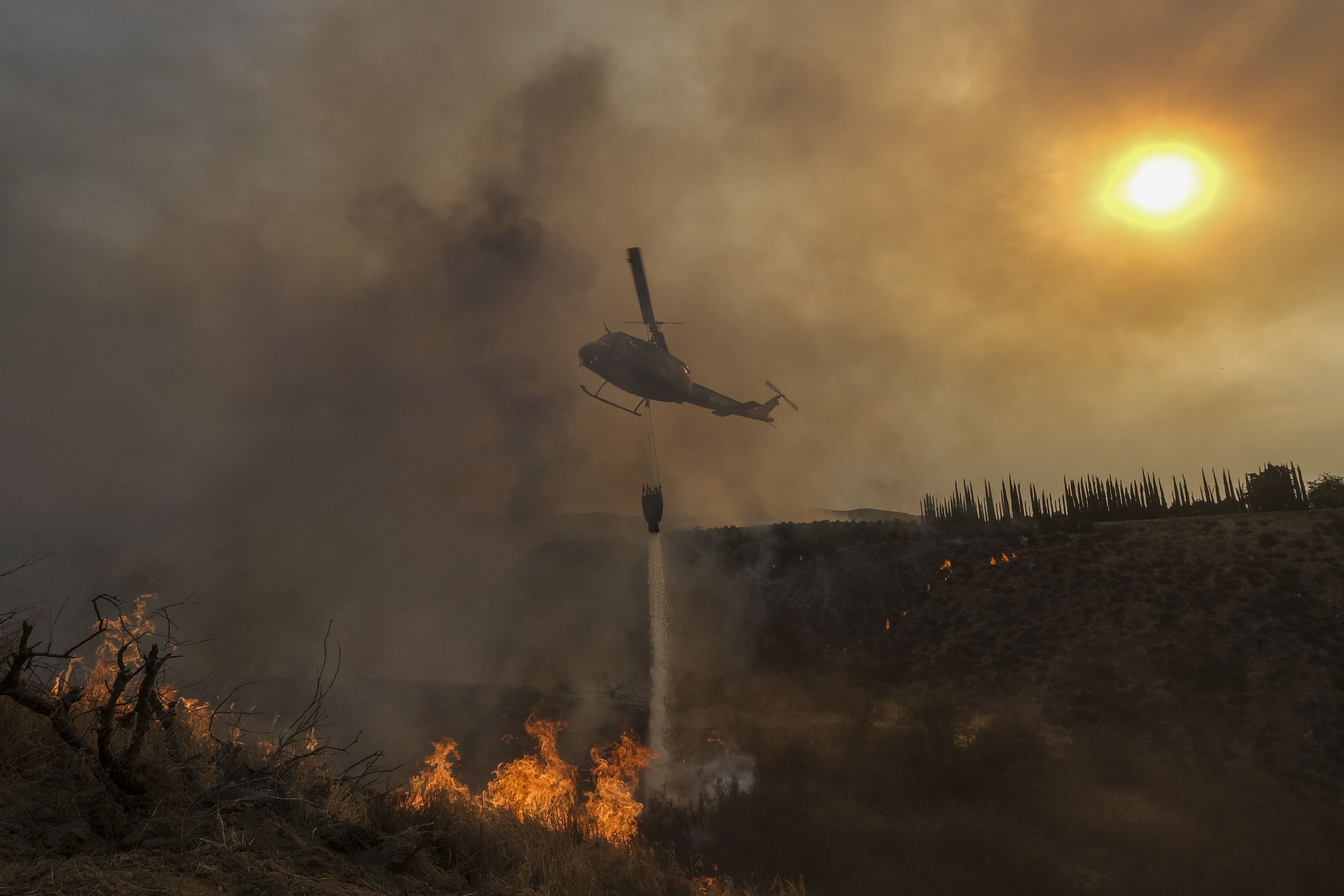 A helicopter drops water on the Fairview Fire burning on a hillside Thursday, Sept. 8, 2022, near Hemet, Calif. Scientists say a warming planet will lead to hotter, longer and more wildfire-plagued heat waves.