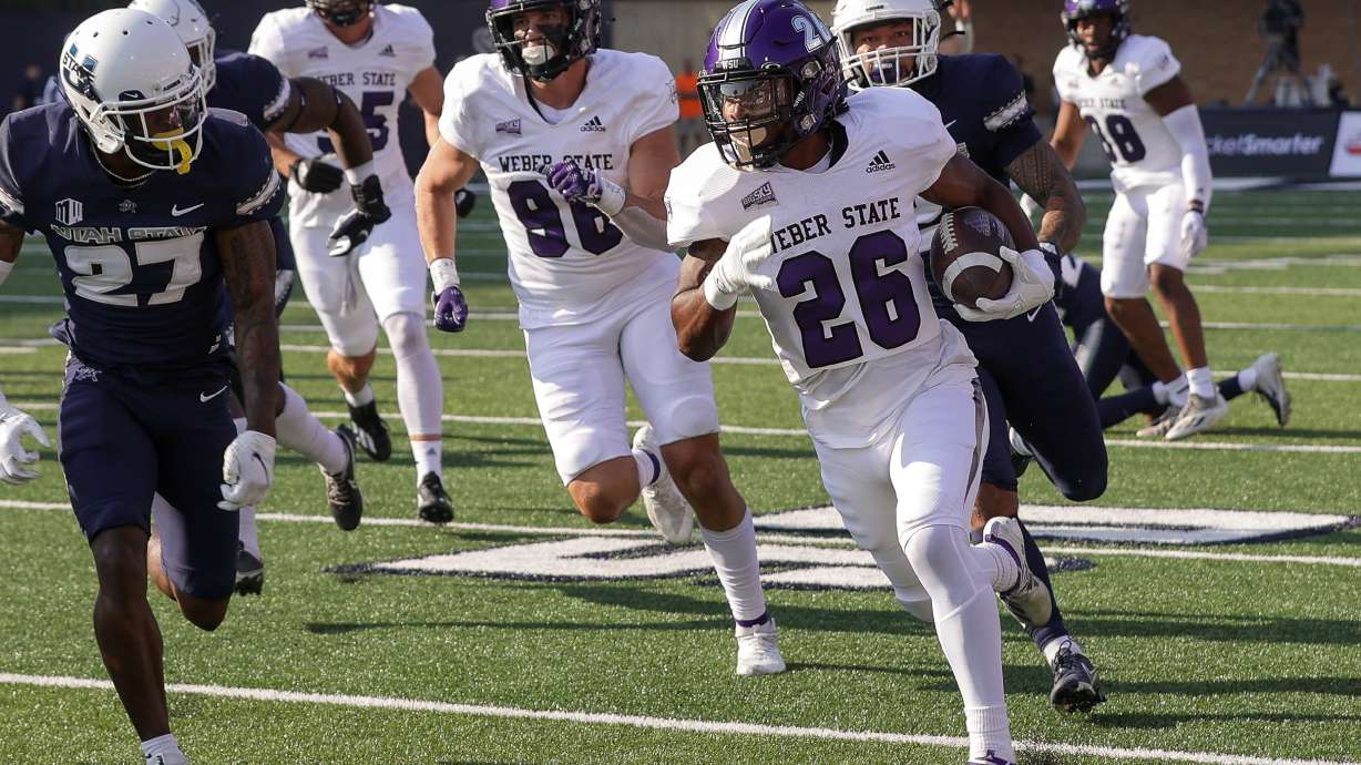 Running back Damon Bankston runs away from Utah State defenders in a game the Wildcats won, 35-7, on Sept. 10, 2022.