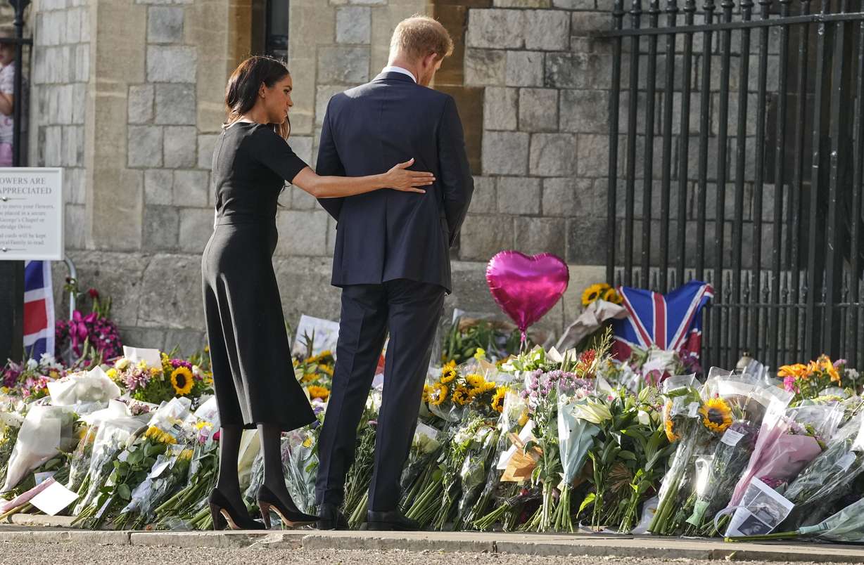 Prince Harry and Meghan, Duchess of Sussex, look at the floral tributes for the late Queen Elizabeth II outside Windsor Castle, in Windsor, England, Saturday.