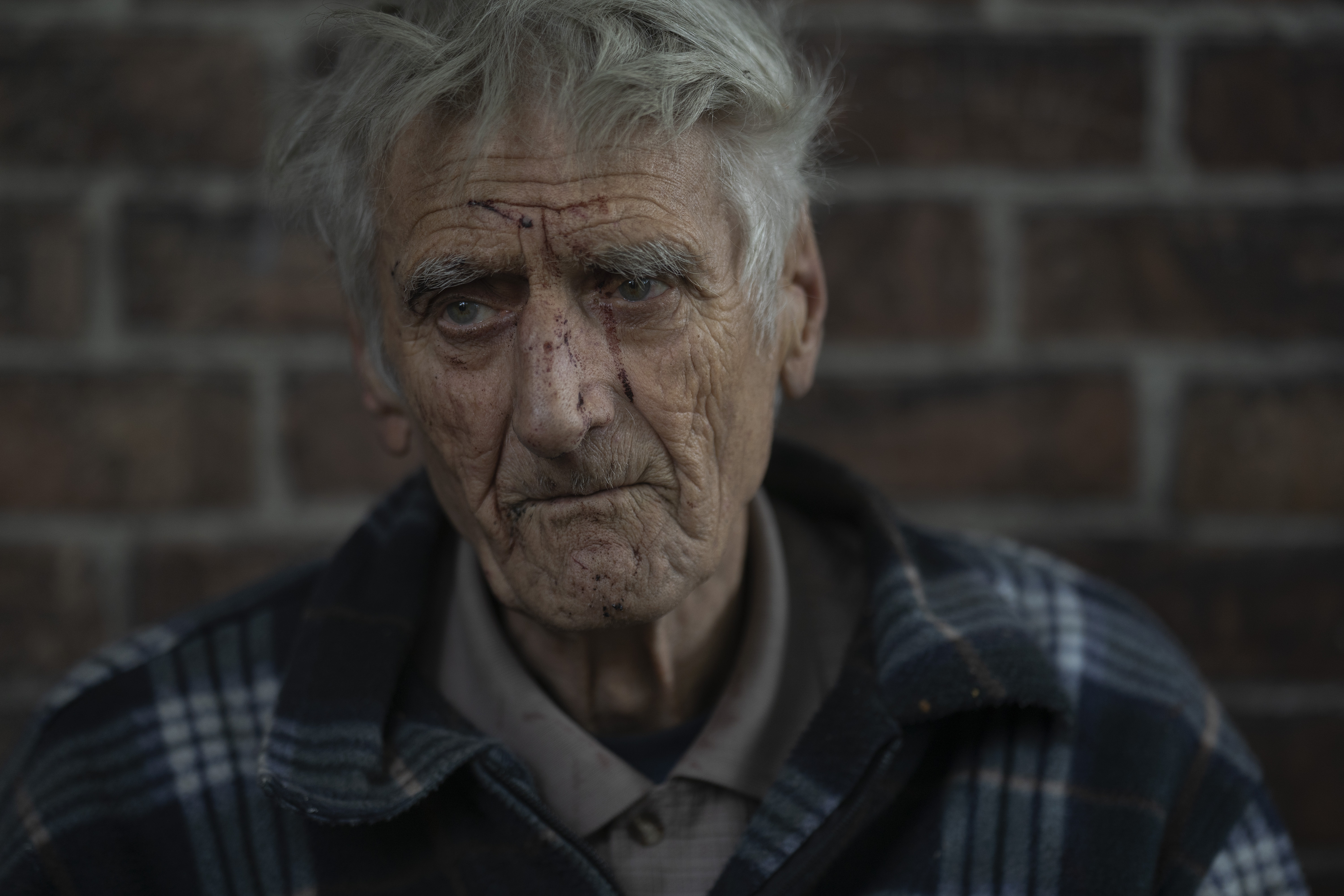 Oleksii Maksymenko looks on as he sits at the entrance of his house that was damaged after a Russian attack in Pokrovsk region, Ukraine, Sunday. The 75-year-old retired coal miner, who couldn't hear the explosion due to his hearing loss condition, woke up covered with debris as he was sleeping with his wife Mariia Trutko, 85.