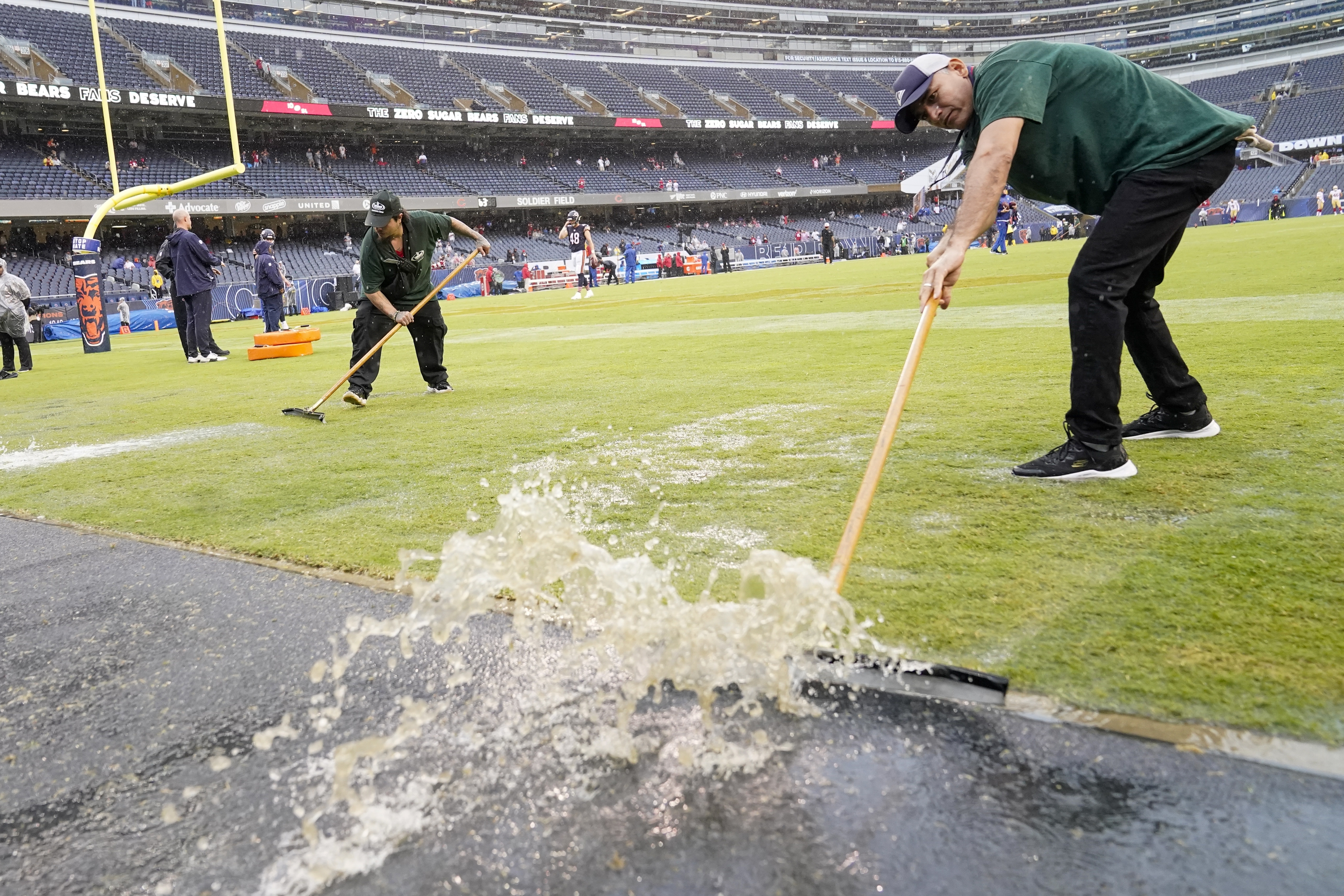 Workers remove water from Soldier Field before an NFL football game between the Chicago Bears and the San Francisco 49ers Sunday, Sept. 11, 2022, in Chicago. 