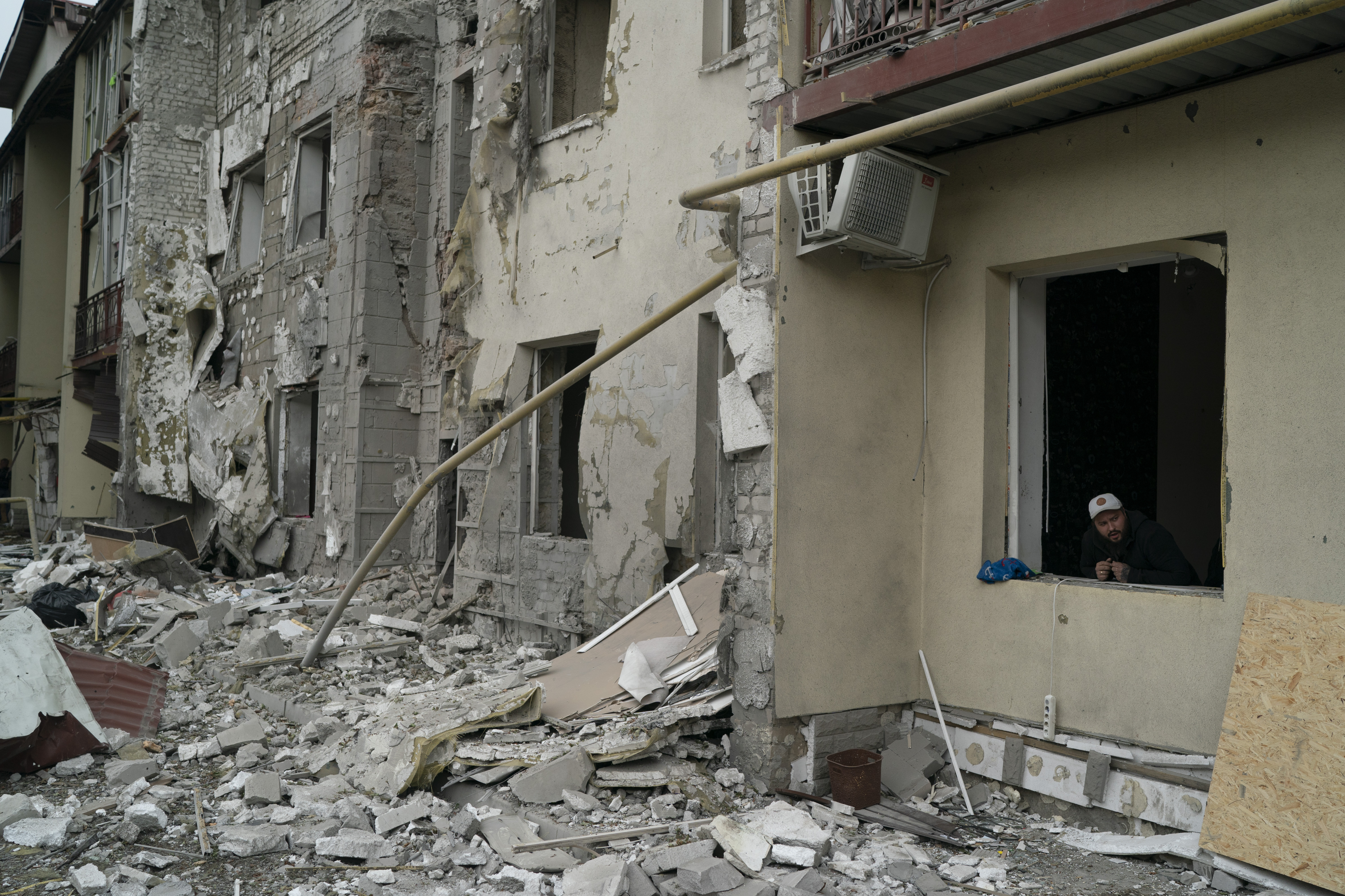 A man looks out from a window of a residential building that was damaged after a Russian attack in Kharkiv, Ukraine, Monday.