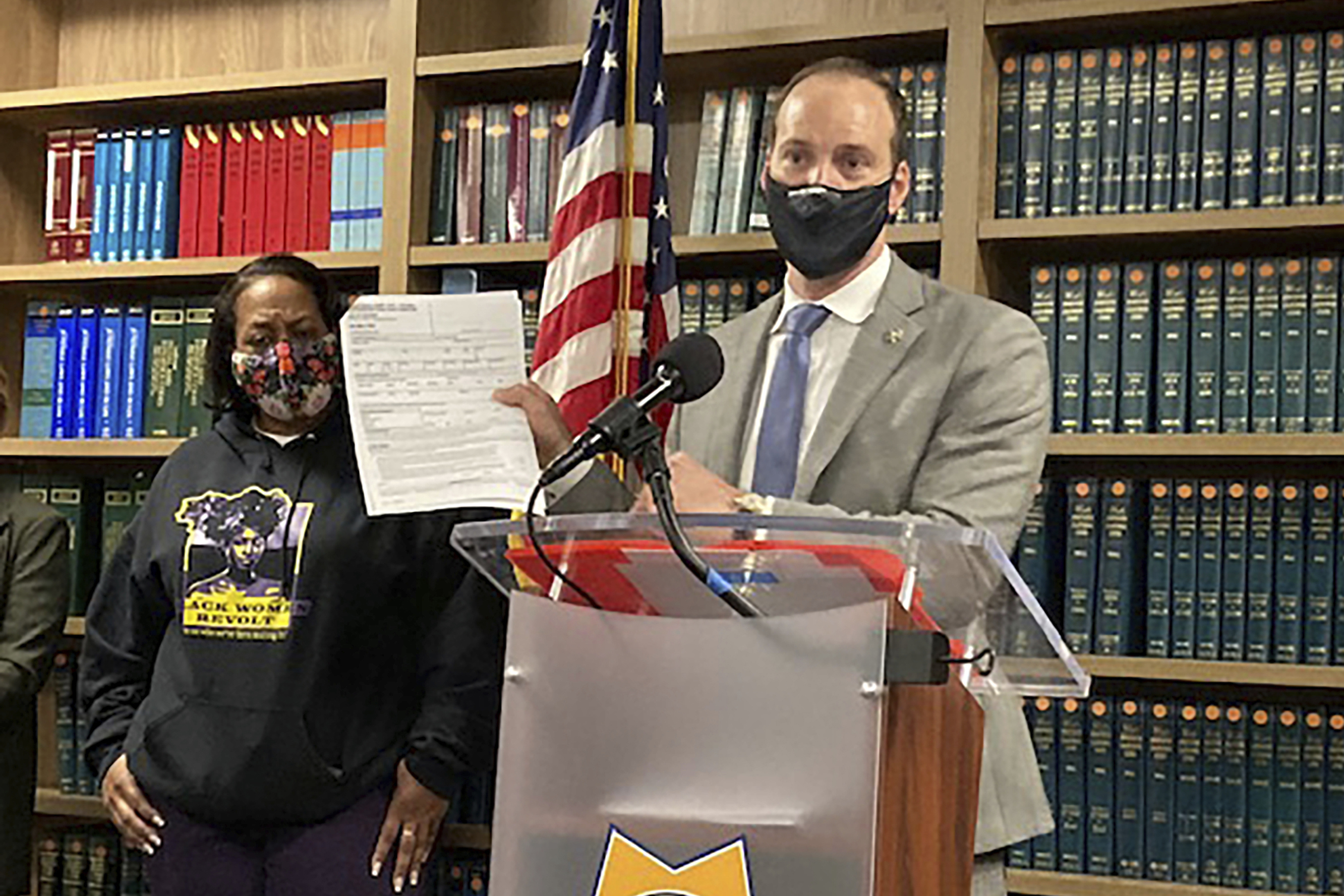 Former San Francisco District Attorney Chesa Boudin holds a report during a news conference in San Francisco on Feb. 15. Boudin said the report showed DNA collected by San Francisco police from a woman who was sexually assaulted was used by police detectives to arrest her years later in an unrelated property crime. Attorney Adante Pointer said Monday he has filed a lawsuit against San Francisco on the woman's behalf. 