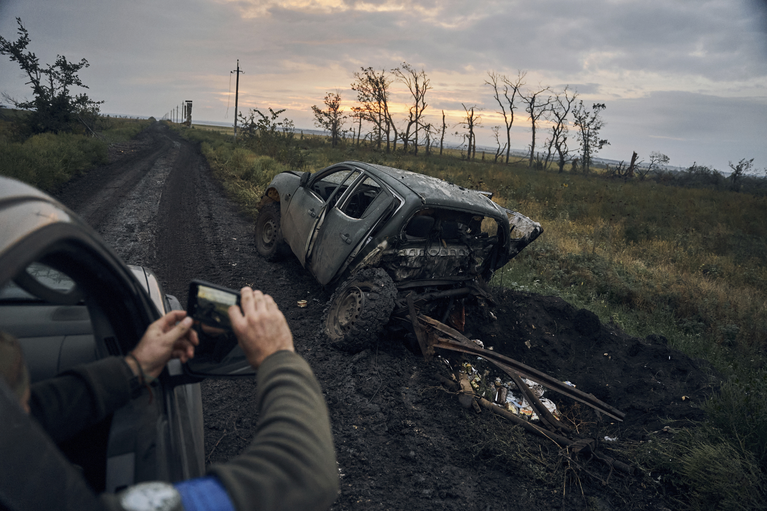 A Ukrainian soldier takes a photo of a burnt car on the road in the freed territory in the Kharkiv region, Ukraine, Monday. Ukrainian troops retook a wide swath of territory from Russia on Monday, pushing all the way back to the northeastern border in some places.