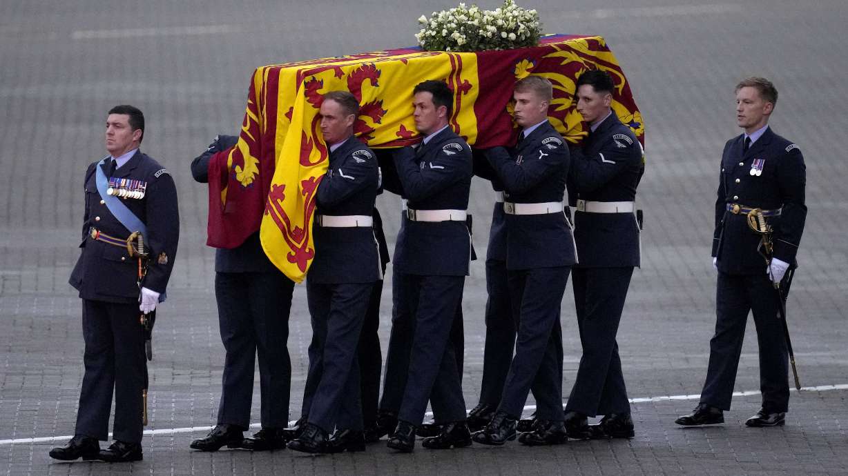 The coffin of Queen Elizabeth II is carried off a plane by the Queen's Colour Squadron at RAF Northolt in London, to be taken to Buckingham Palace, Tuesday. Queen Elizabeth II, Britain's longest-reigning monarch and a rock of stability across much of a turbulent century, died Thursday after 70 years on the throne. She was 96.