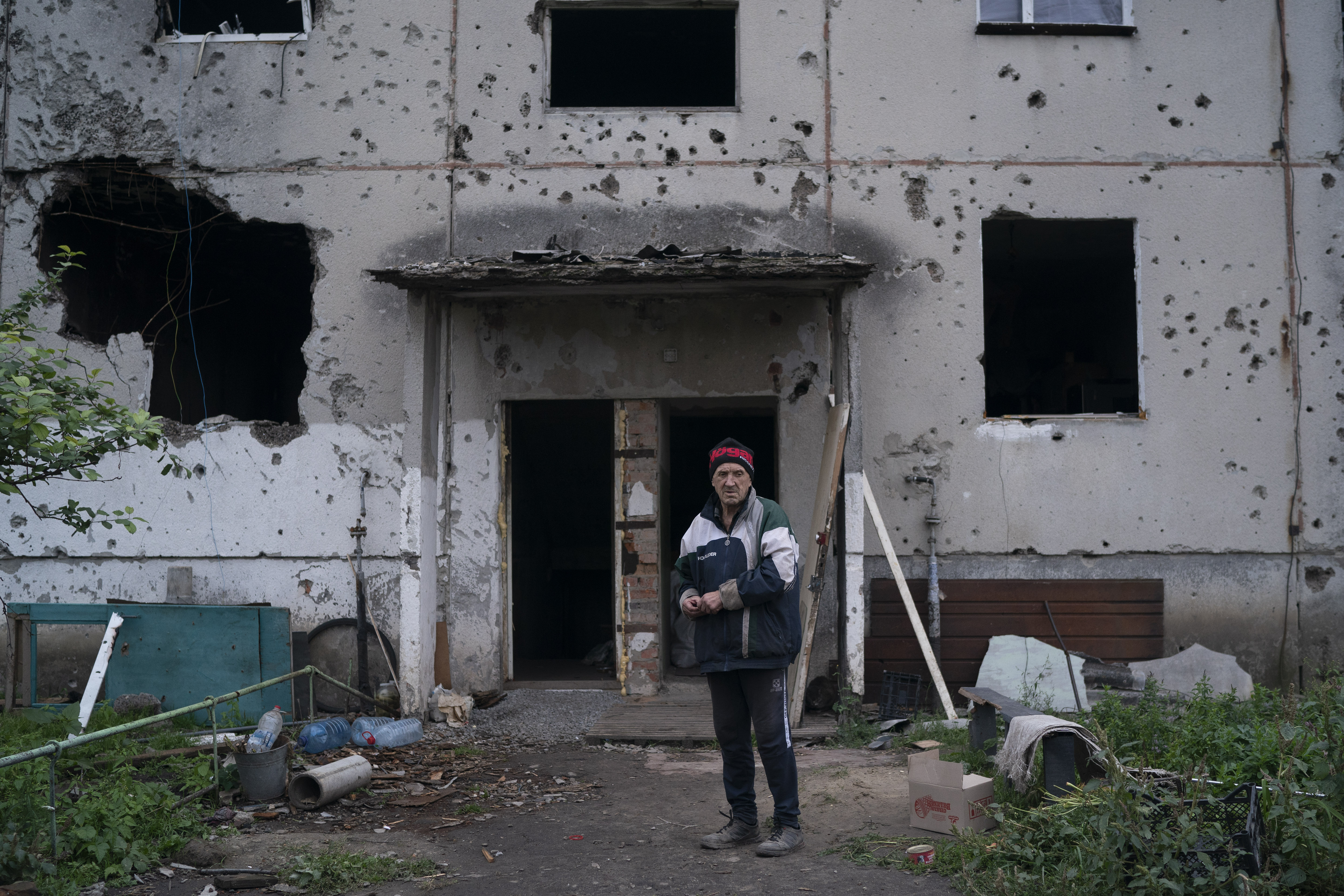 Oleh Lutsai, 70, stands in front of the entrance of the damaged building where he lives in the freed village of Hrakove, Ukraine, Tuesday. Lutsai has been living in the basement for months together with other neigbhors.