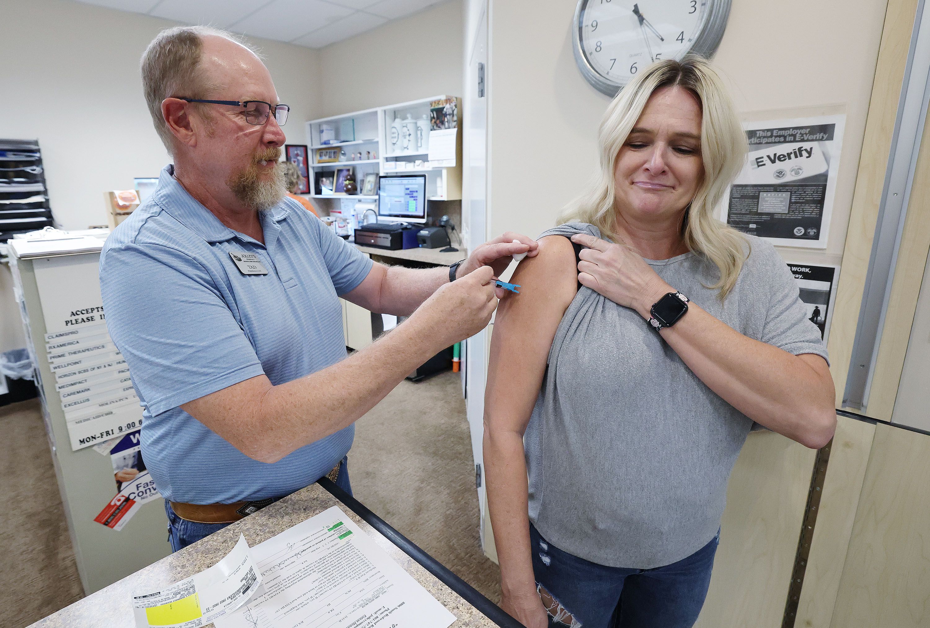 Pharmacist Tad Jolley vaccinates gift shop employee Kamie White with a flu shot at Jolley’s Pharmacy in West Jordan on Tuesday. Flu shots aren't something most people think about until later in the fall or even winter. But that's changing this year now that everyone is being urged to get the newly updated COVID-19 booster shots as soon as they're eligible.