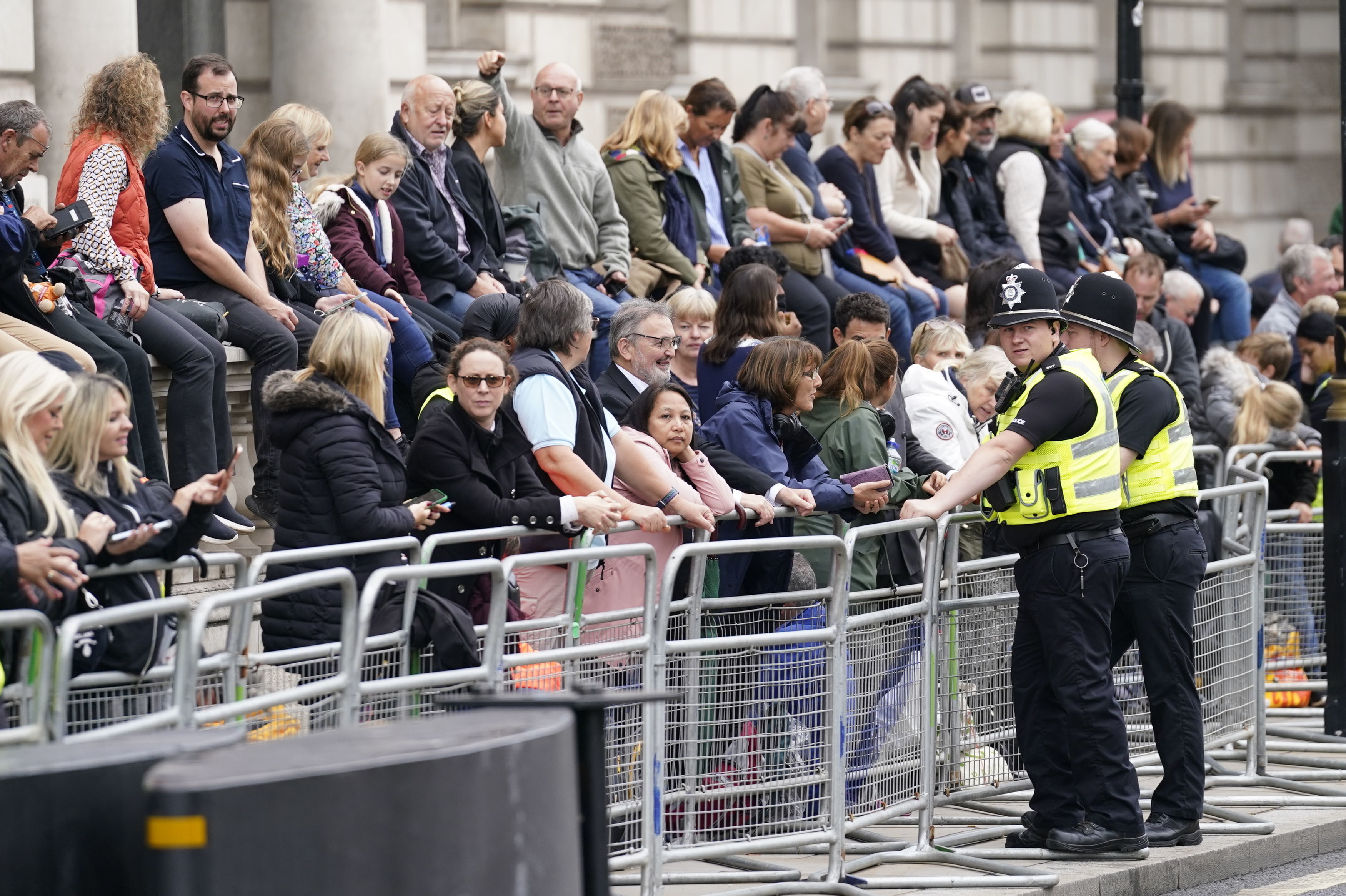 People wait ahead of the ceremonial procession of the coffin of Queen Elizabeth II from Buckingham Palace to Westminster Hall, in in Westminster, central London, Wednesday.