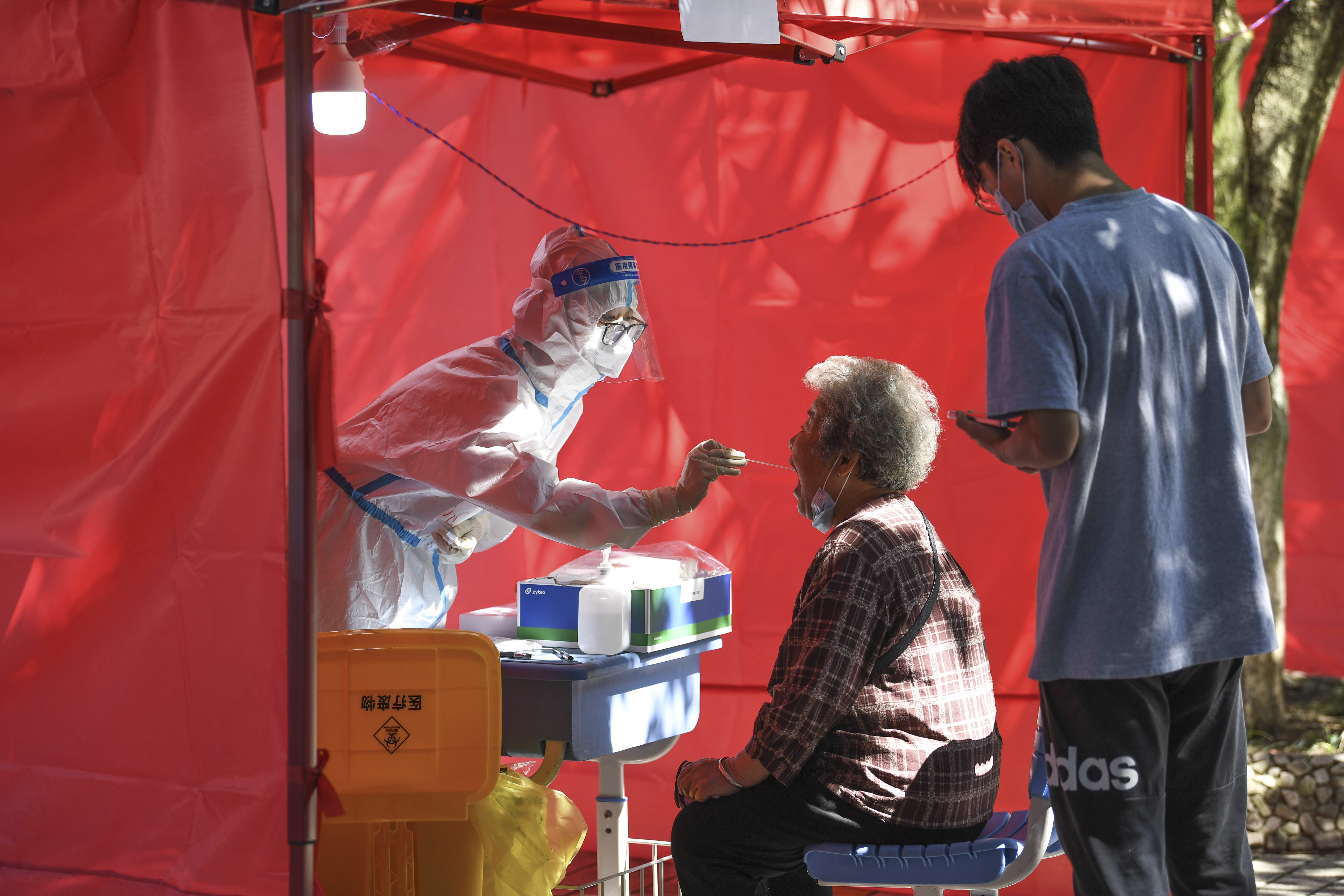 In this photo released by Xinhua News Agency, a medical worker takes a swab sample from a resident for nucleic acid test at a community testing site for COVID-19 in Yunyan District of Guiyang, southwest China's Guizhou Province, Sept. 5. The head of the World Health Organization says the number of coronavirus deaths last week was the lowest reported number in the pandemic since March 2020, marking what could be a turning point in the years-long global outbreak. 