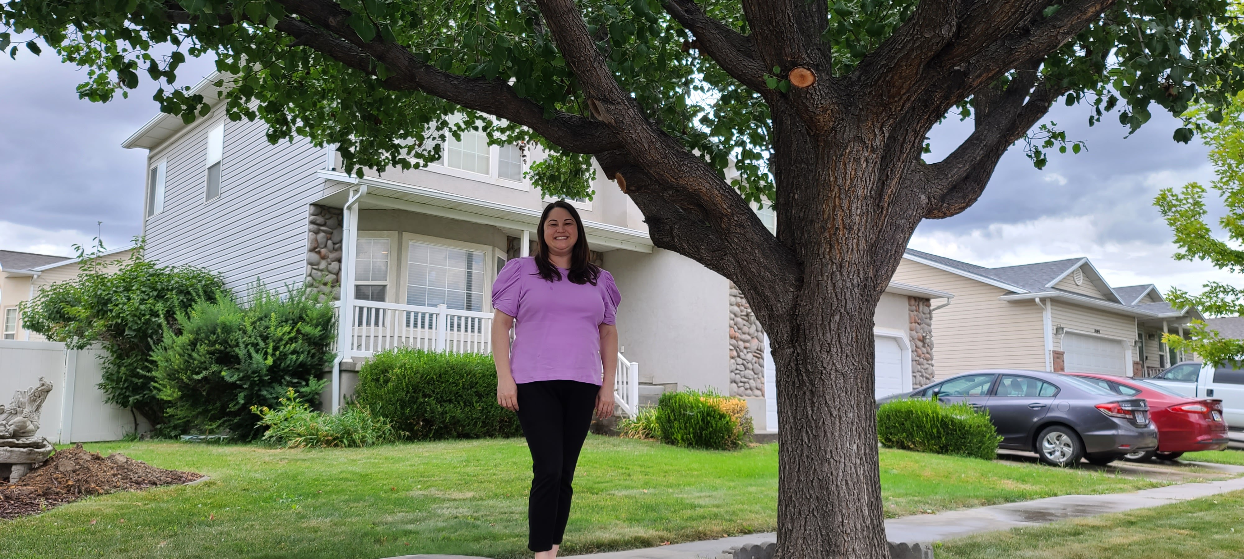 Anne-Marie Mickelsen stands next to a flowering pear tree on the park strip in front of her house in Lehi on Tuesday. Lehi plans to cut down more than 300 trees in the Olympic Park neighborhood, citing liability.