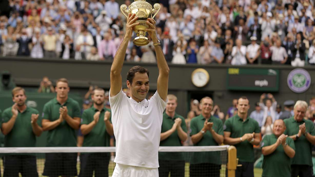 FILE - Switzerland's Roger Federer is applauded by ground staff as he holds the trophy after defeating Croatia's Marin Cilic to win the Men's Singles final match on day thirteen at the Wimbledon Tennis Championships in London Sunday, July 16, 2017. Federer announced Thursday, Sept.15, 2022 he is retiring from tennis.