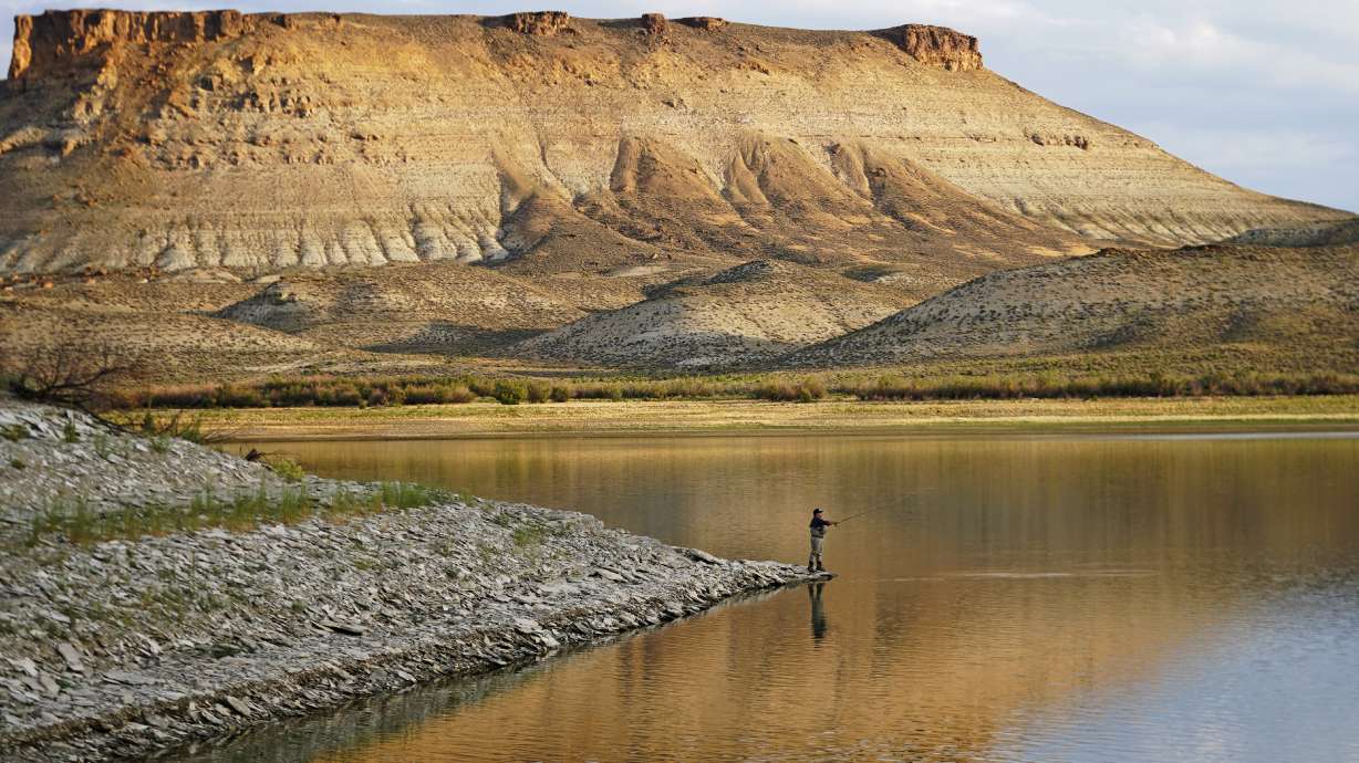 Nick Gann fishes in Firehole Canyon on Aug. 5 on the far northeastern shore of Flaming Gorge Reservoir, in Wyoming. A boating and fishing paradise on the Utah-Wyoming line, Flaming Gorge is beginning to feel the effects of the two-decade megadrought gripping the southwestern U.S.