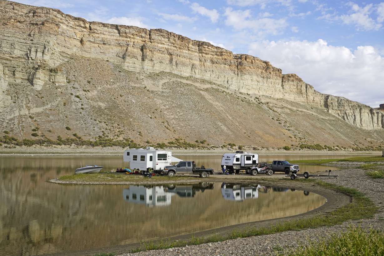 Campers are parked along the receding edge of Flaming Gorge Reservoir on Firehole Canyon on Friday, Aug. 5, 2022, in Wyoming