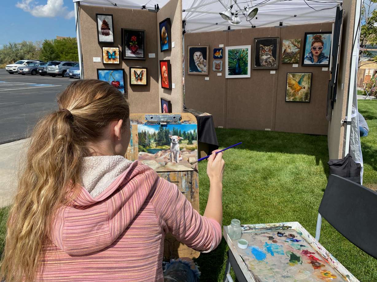 Heather Olsen paints at her booth during Art at The Park at This Is The Place Heritage Park in Salt Lake City on Friday.