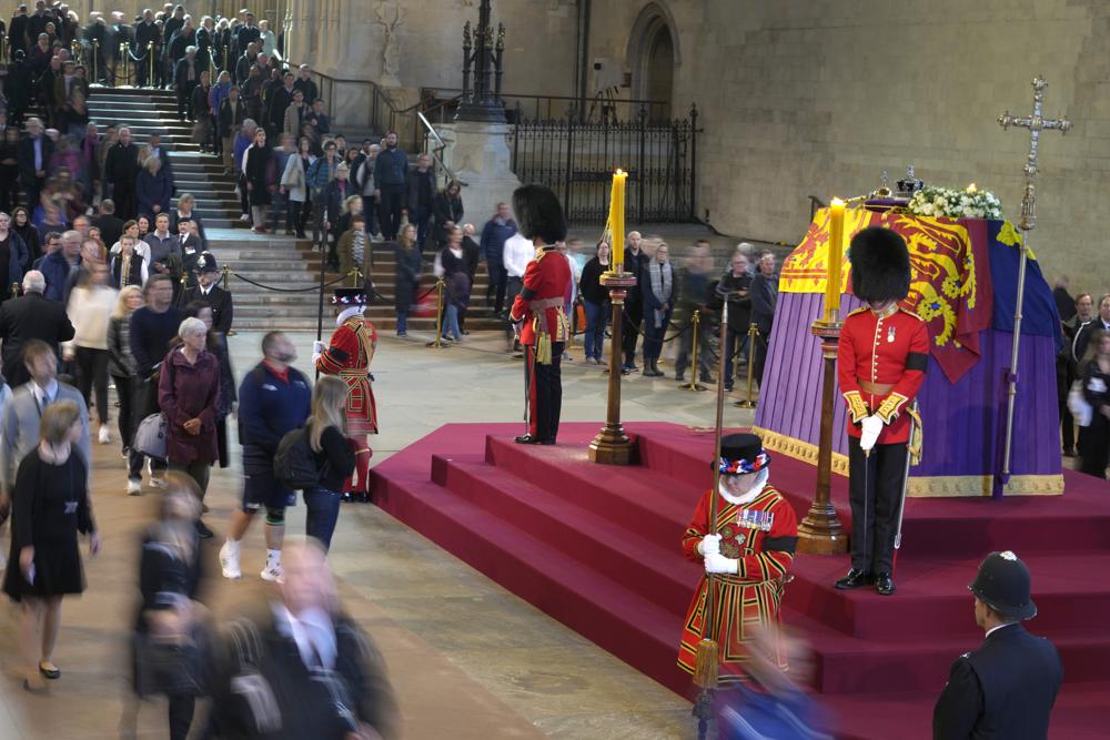 Members of the public file past the coffin of Queen Elizabeth II, draped in the Royal Standard with the Imperial State Crown and the Sovereign's orb and sceptre, lying in state on the catafalque, in Westminster Hall, at the Palace of Westminster, in London, Friday, ahead of her funeral on Monday.