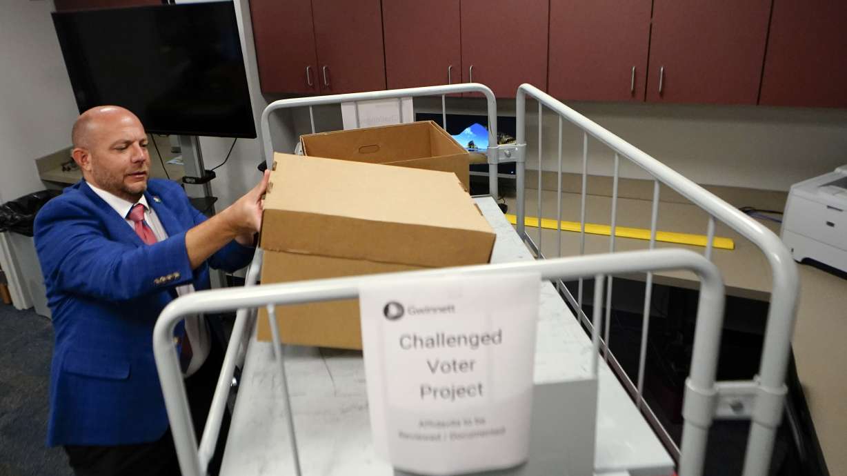 Gwinnett County elections supervisor Zach Manifold looks over boxes of voter challenges on Thursday, in Lawrenceville, Ga. Manifold estimated his office has a month to log and research the challenges, before mail ballots go out for the November elections. “It is a tight window to get everything done,” he said.