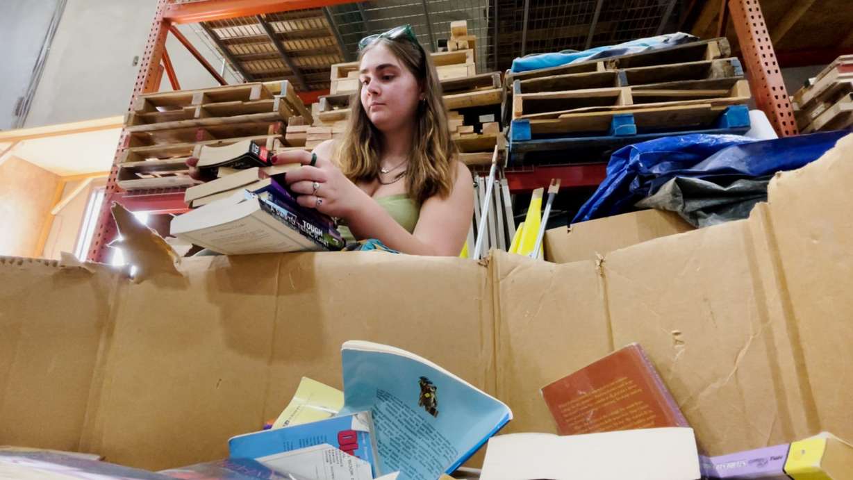 A volunteer at Tiny Tim’s Toy Factory in West Jordan sorts through book donations.