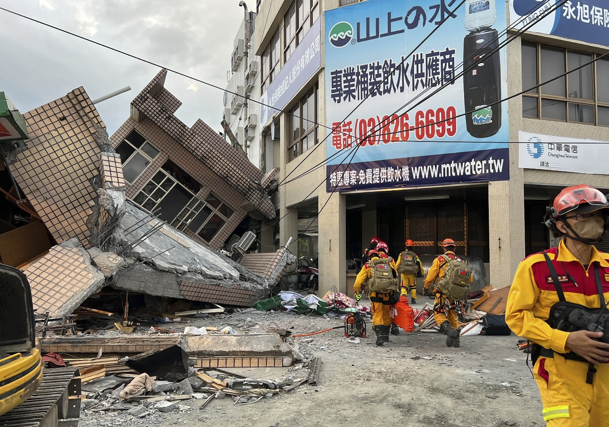 Firefighters search Sunday for trapped victims in a collapsed residential building following earthquake in Yuli township in Hualien County, Taiwan. A strong earthquake shook much of Taiwan on Sunday, toppling at least one building and trapping two people inside and knocking part of a passenger train off its tracks at a station.