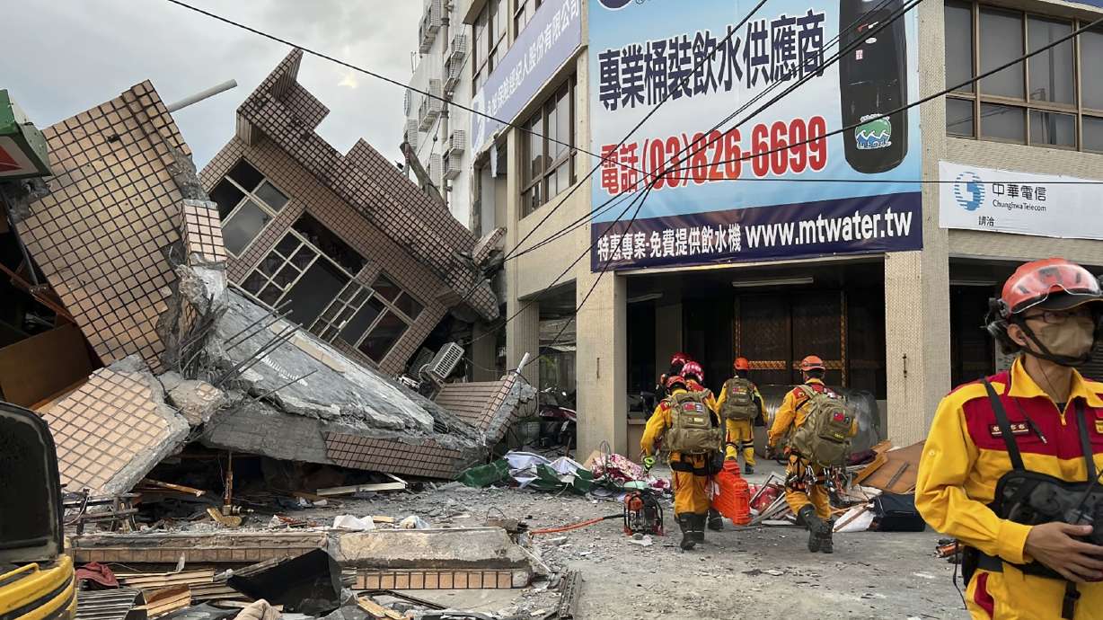 Firefighters search Sunday for trapped victims in a collapsed residential building following earthquake in Yuli township in Hualien County, Taiwan. A strong earthquake shook much of Taiwan on Sunday, toppling at least one building and trapping two people inside and knocking part of a passenger train off its tracks at a station.