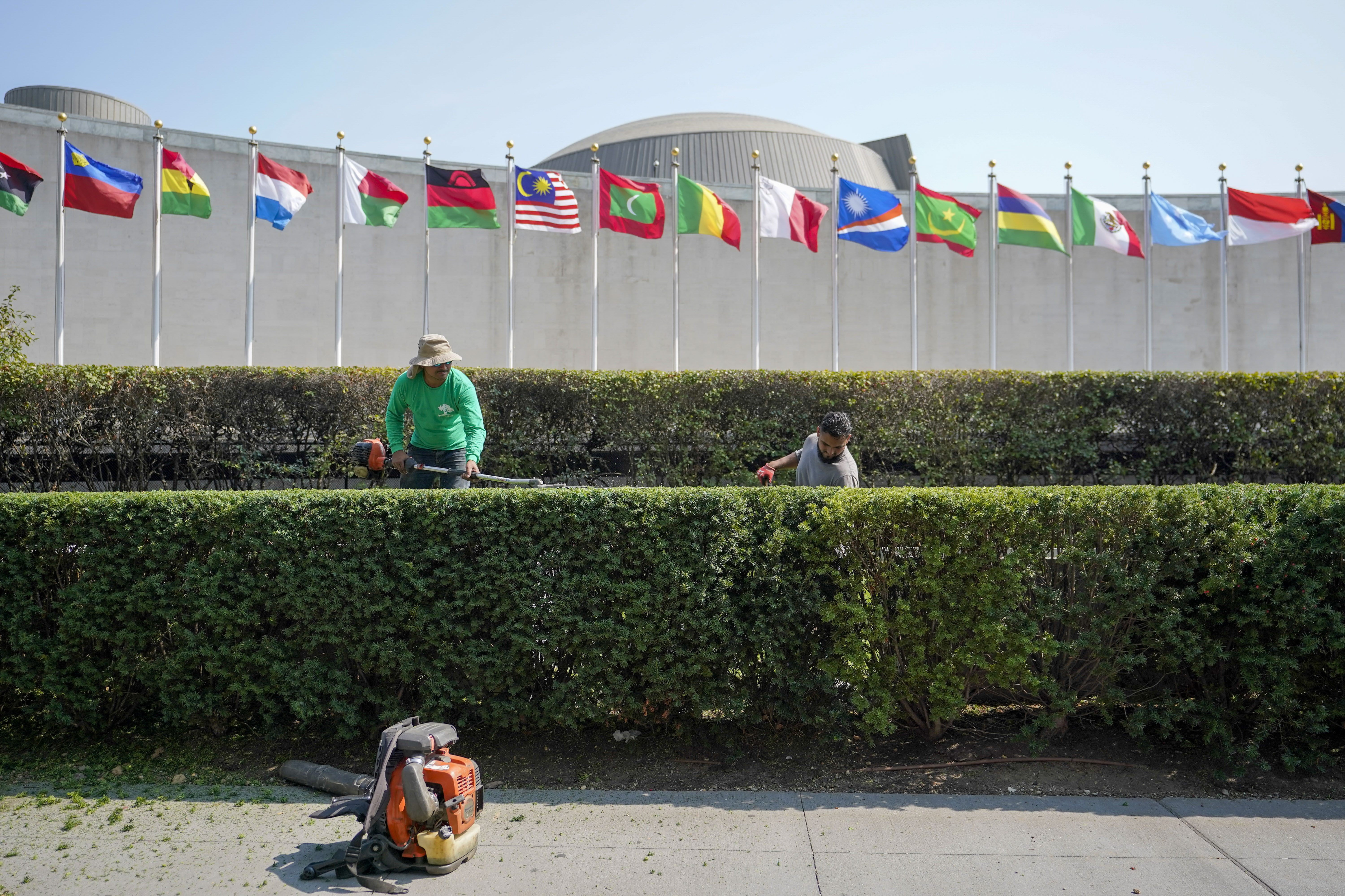 Workers trim the hedges outside the General Assembly building at the United Nations headquarters ahead of the General Assembly, Friday.