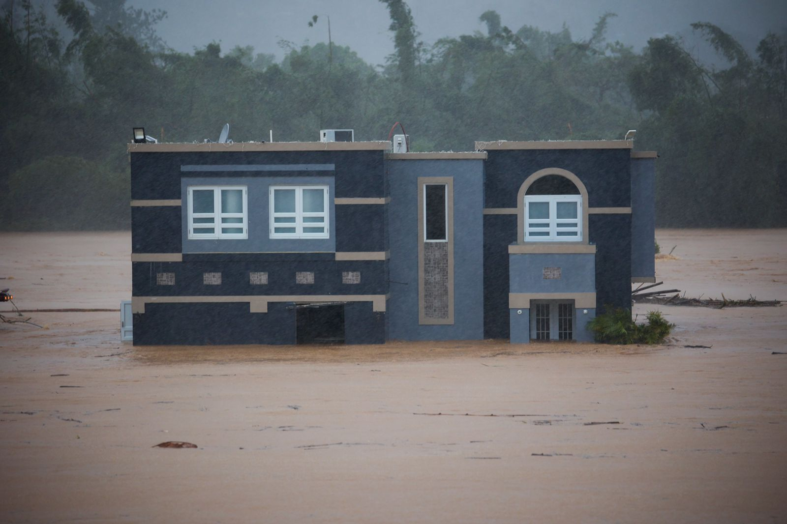 Three people inside a house await rescue from the floods caused by Hurricane Fiona in Cayey, Puerto Rico, Sunday.