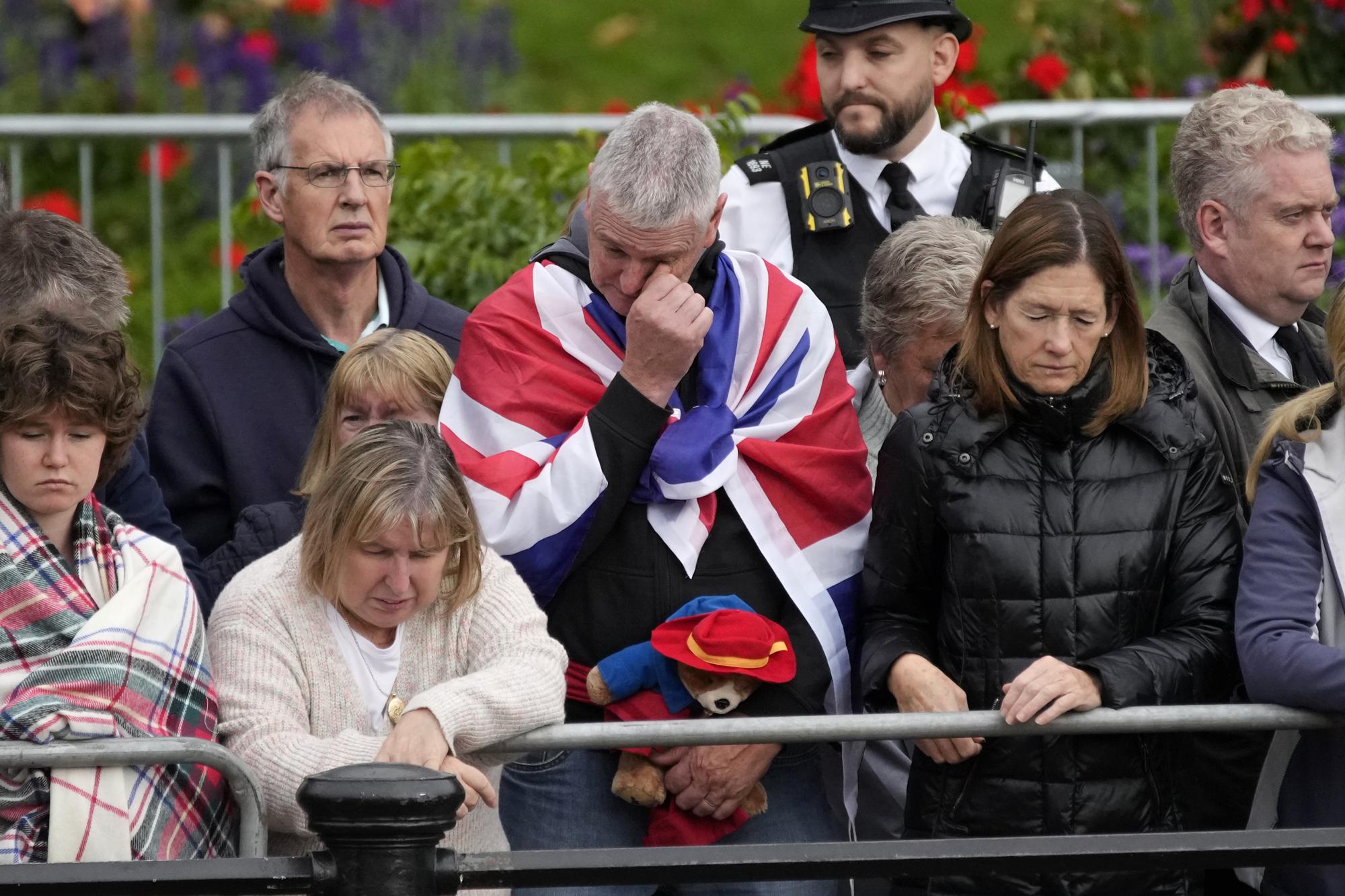 A person holding a Paddington Bear stuffed toy stands with members of the public outside Buckingham Palace waiting to watch Queen Elizabeth II funeral procession, in central London Monday. The Queen, who died aged 96 on Sept. 8, will be buried at Windsor alongside her late husband, Prince Philip, who died last year.