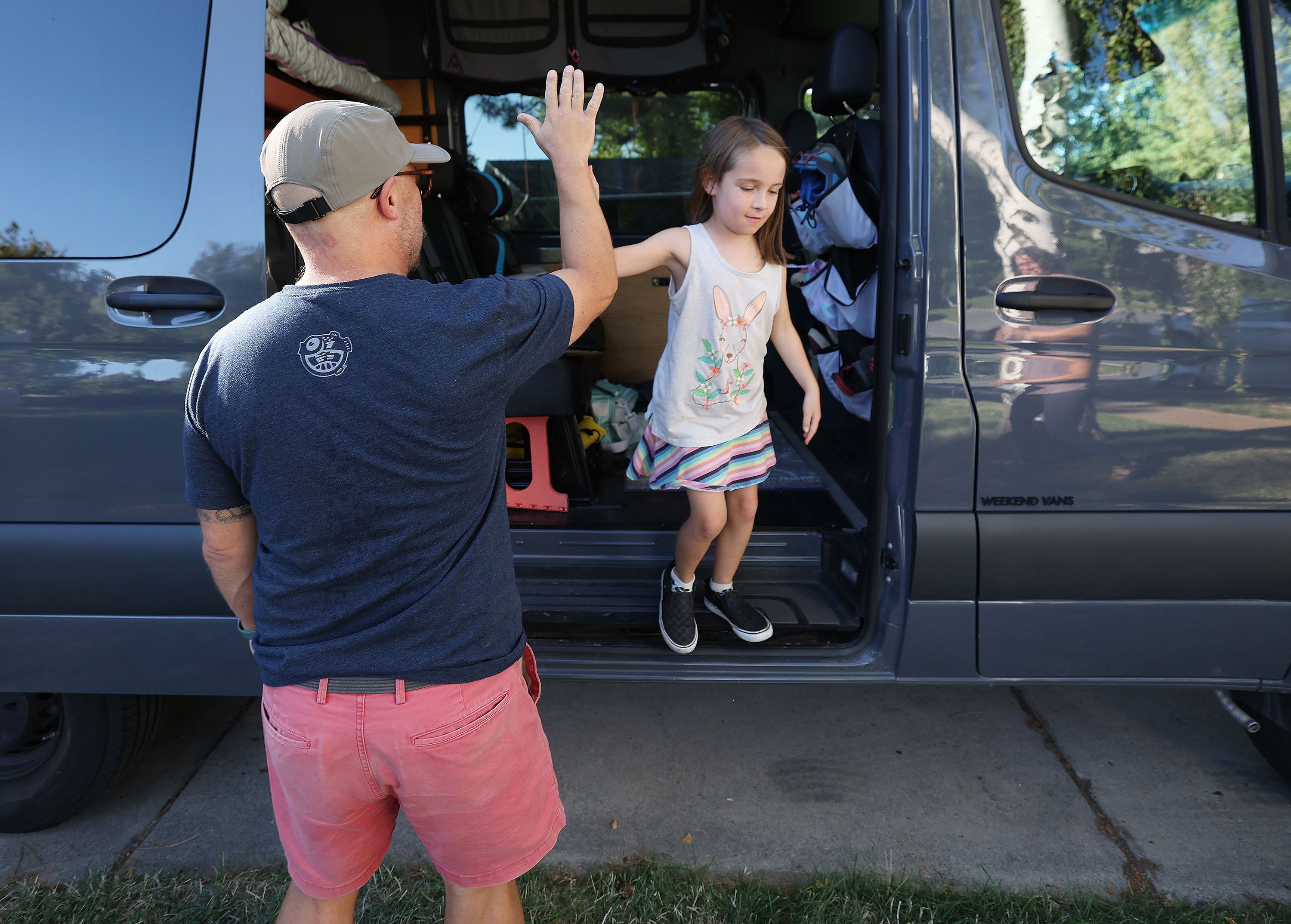 Jason Miller high-fives his daughter, Teagan, 8, as they pack for a family road trip at their home in Murray on Sept. 2. The family is set to load the tricked-out van they call "the camper" for a road trip weekend of camping and a music festival.