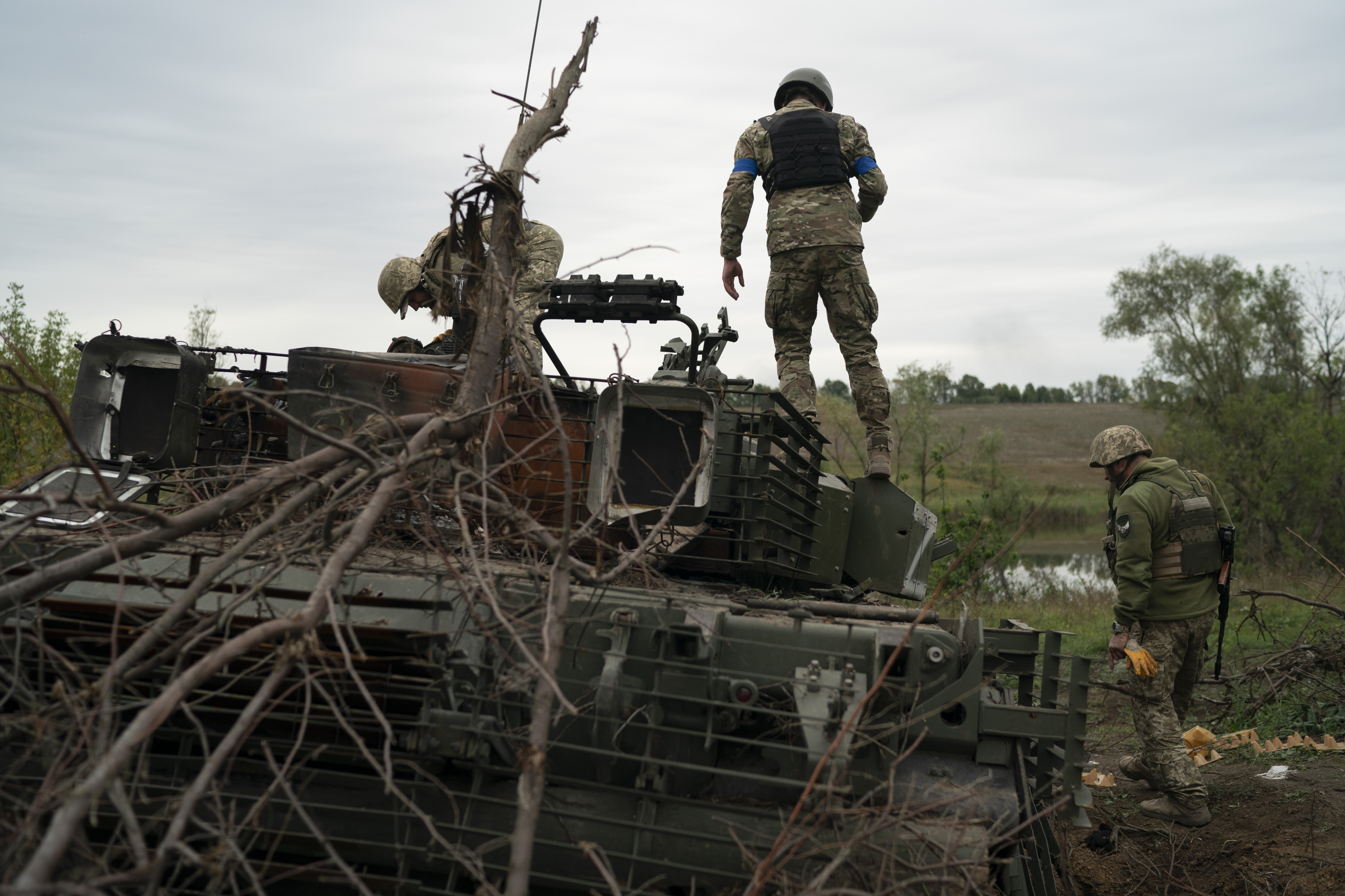 Ukrainian servicemen stand atop a destroyed Russian tank in a retaken area near the border with Russia in Kharkiv region, Ukraine, Saturday.