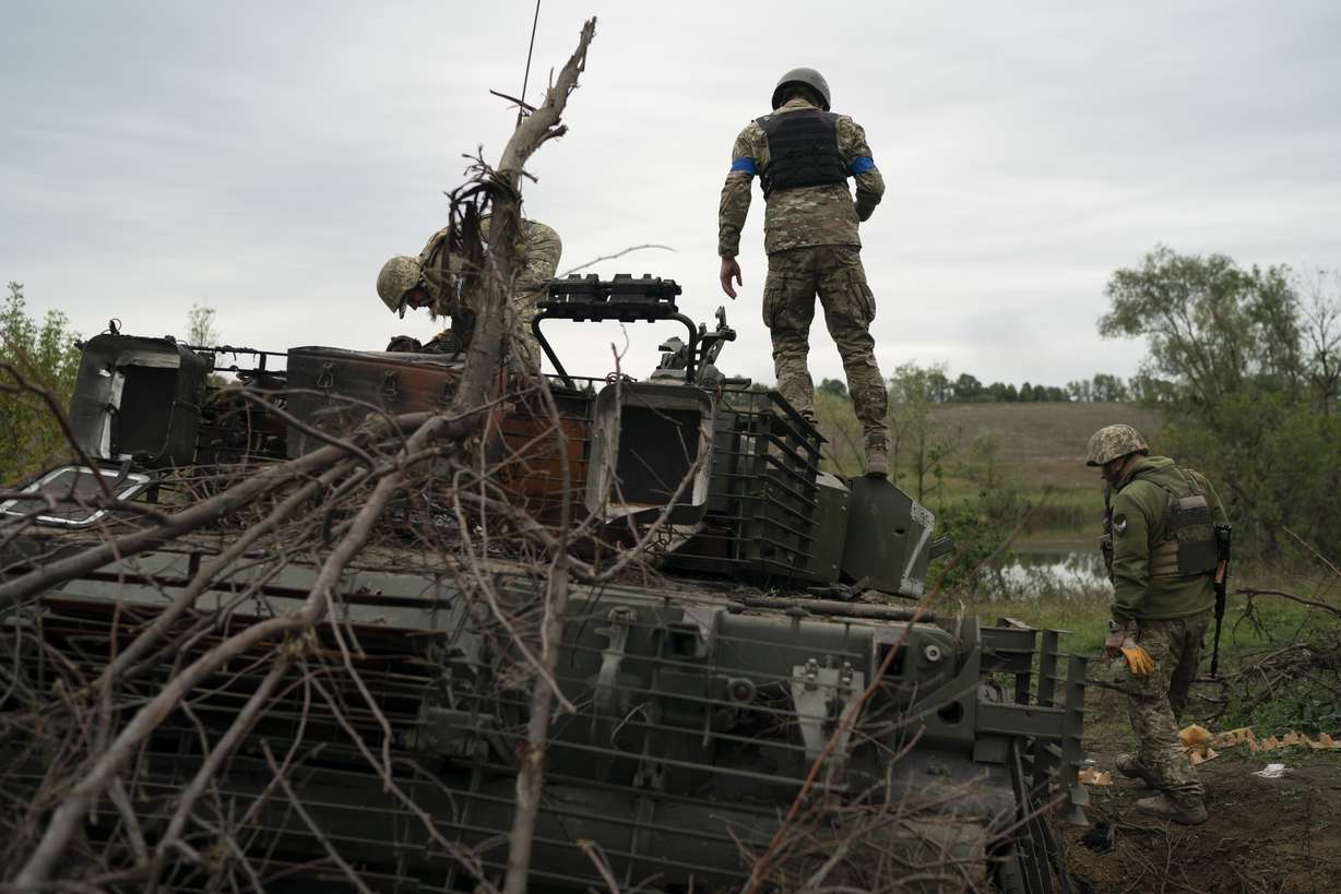 Ukrainian servicemen stand atop a destroyed Russian tank in a retaken area near the border with Russia in Kharkiv region, Ukraine, Saturday.
