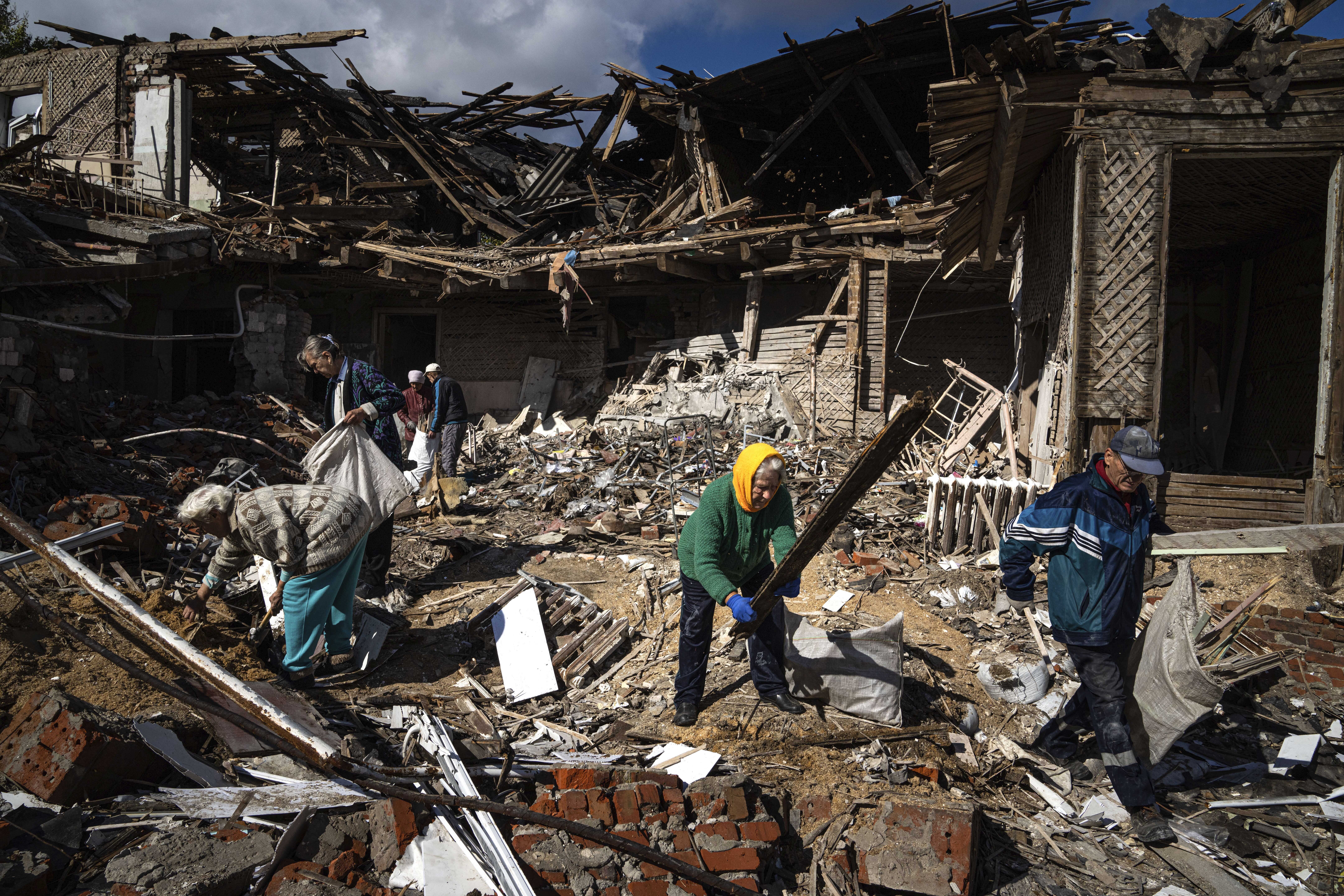 Local residents collect wood for heating from a destroyed school where Russian forces were based, in the recently retaken area of Izium, Ukraine, Monday.