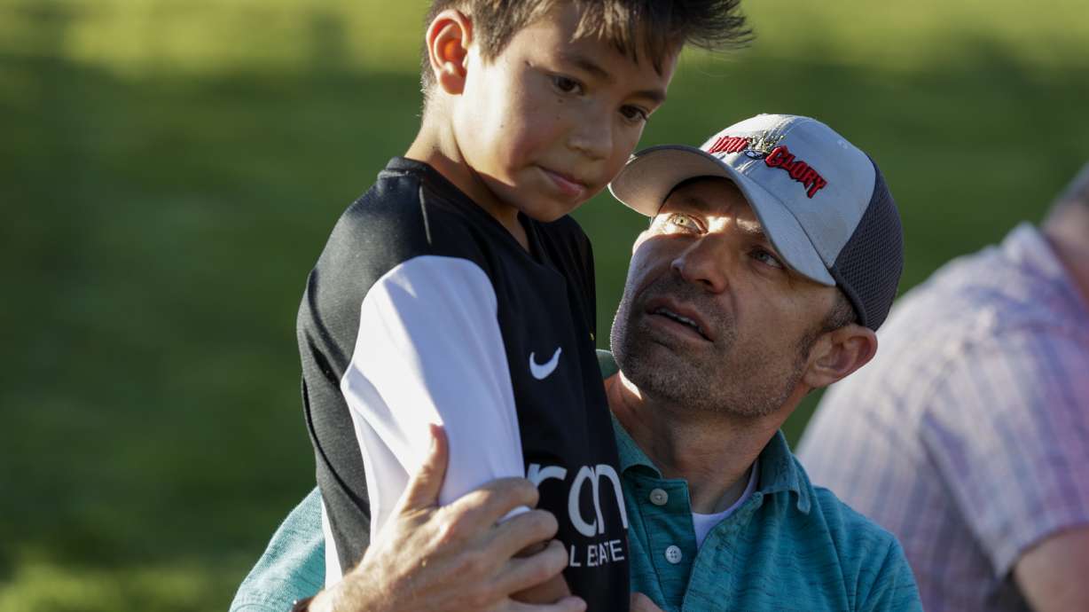 Richard Nuffer holds his son Lynx, 8, during halftime as his team, Utah Glory, plays the Cottonwood Football Club in South Jordan on Monday.