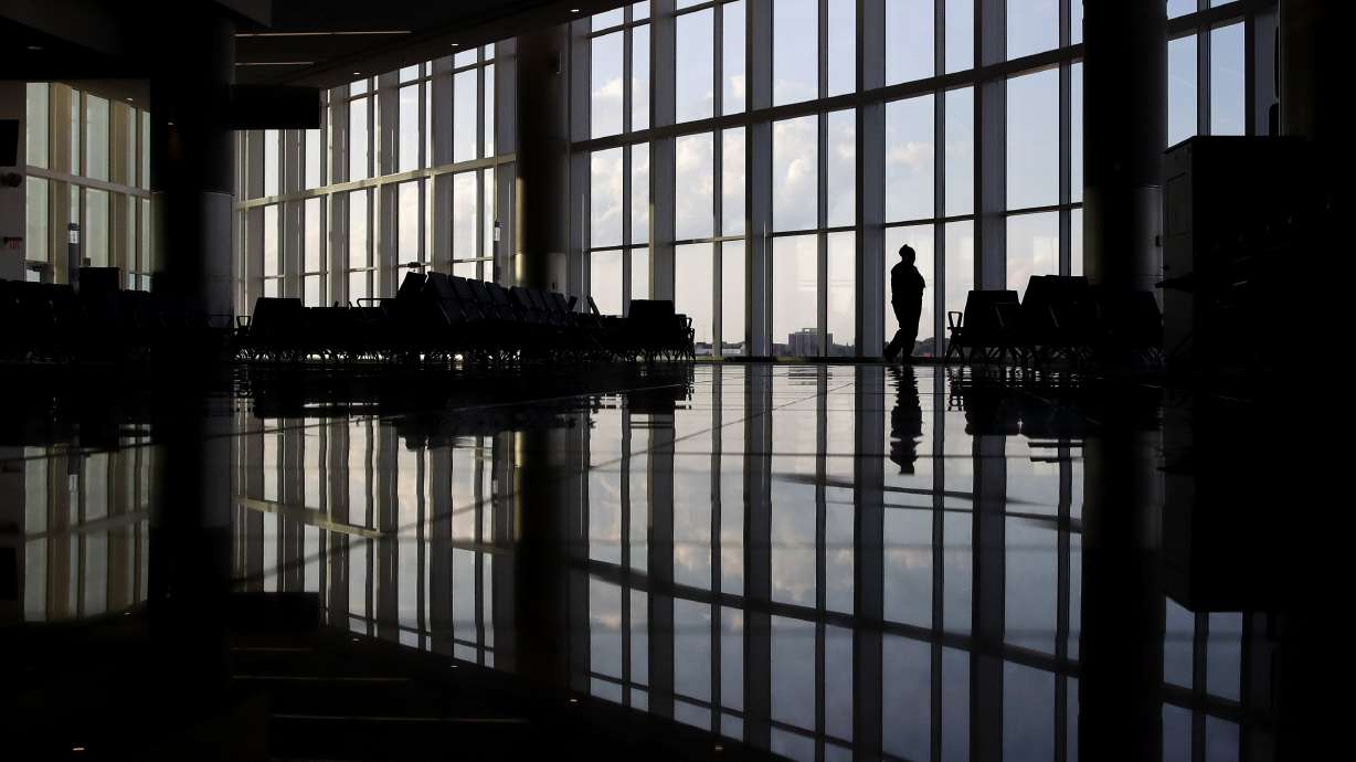 A woman looks through a window at a near-empty terminal at an airport in Atlanta, June 1, 2020. An influential health guidelines group says U.S. doctors should regularly screen adults for anxiety. It’s the first time the U.S. Preventive Services Task Force has recommended anxiety screening in primary care for adults without symptoms.