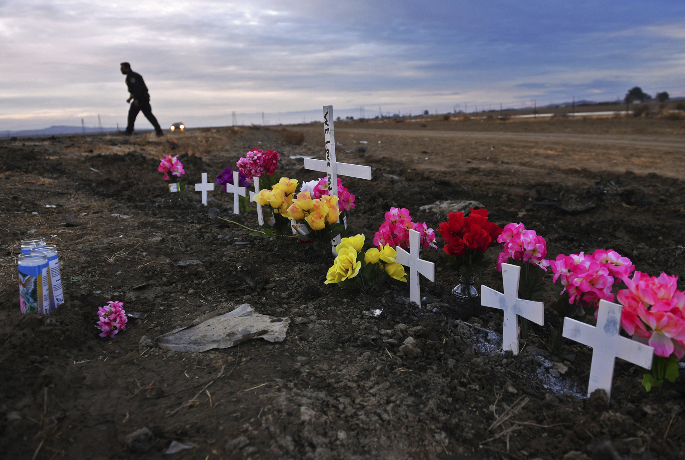 A row of crosses form a memorial along Highway 33 as police officers survey the scene a day after a crash killed nine people south of Coalinga, Calif., Jan. 2, 2021. Investigators said the driver of an SUV involved in the crash was drunk and didn't have a license. The National Transportation Safety Board will use a final report on the crash to launch an effort to lobby for regulations requiring alcohol breath testing devices on all new vehicles. 